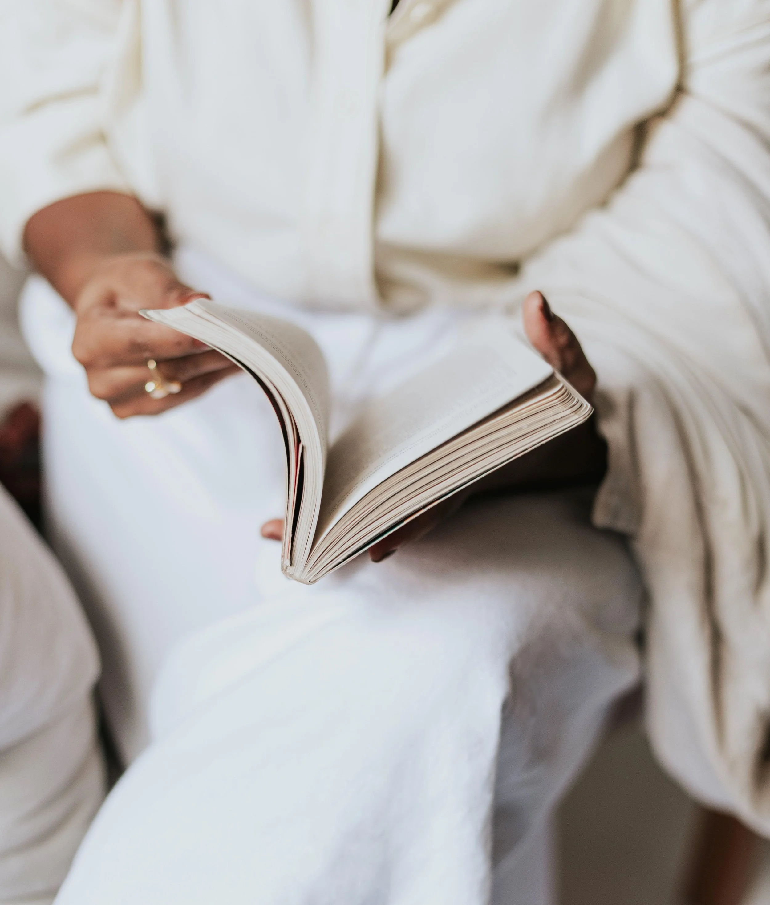 A Supervisor wearing a cream coloured shirt and white pants reads a book