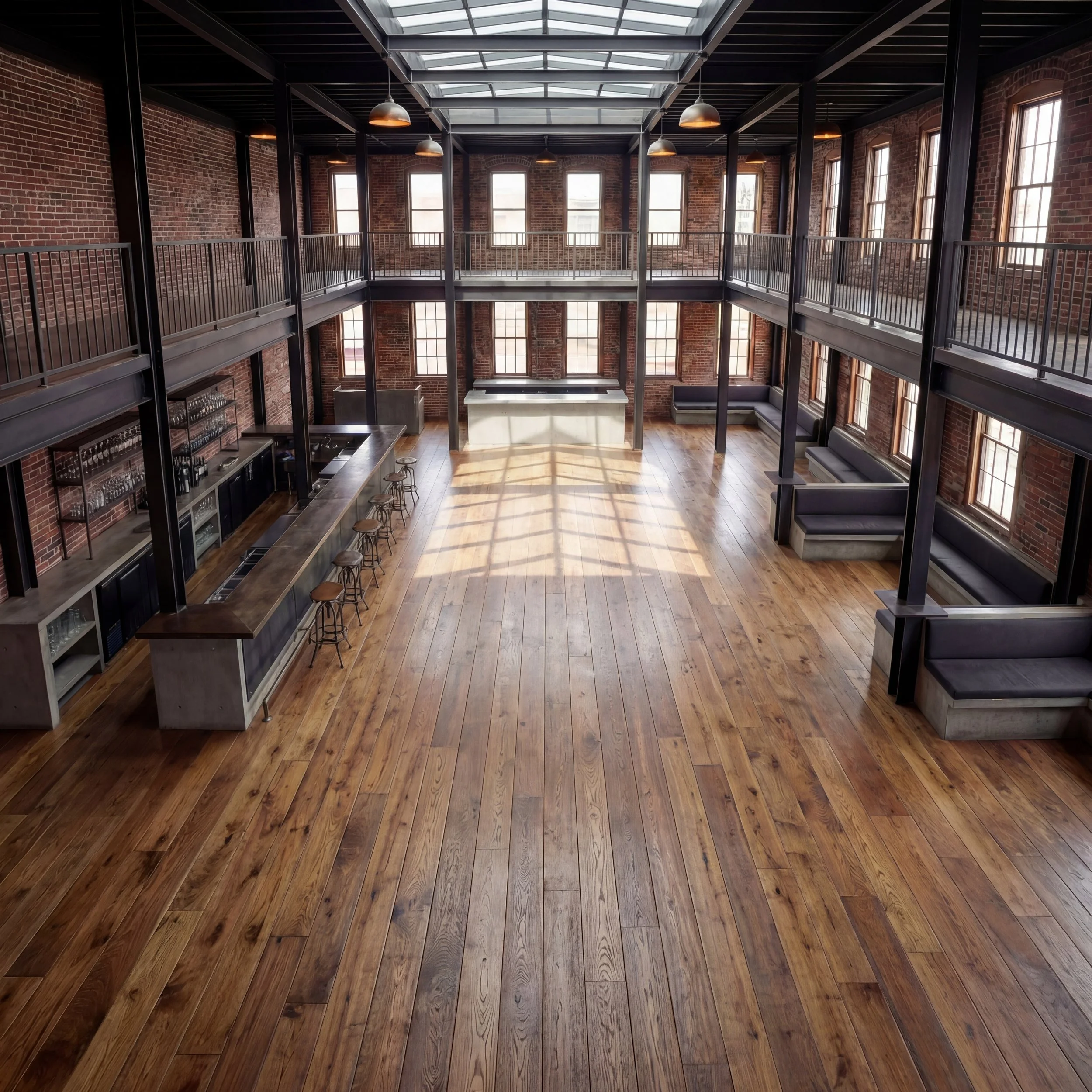 Interior of a rustic-style restaurant with wooden beams, large windows, and dim lighting. Tables are set with plates, glasses, and candles, with green plants as decor.