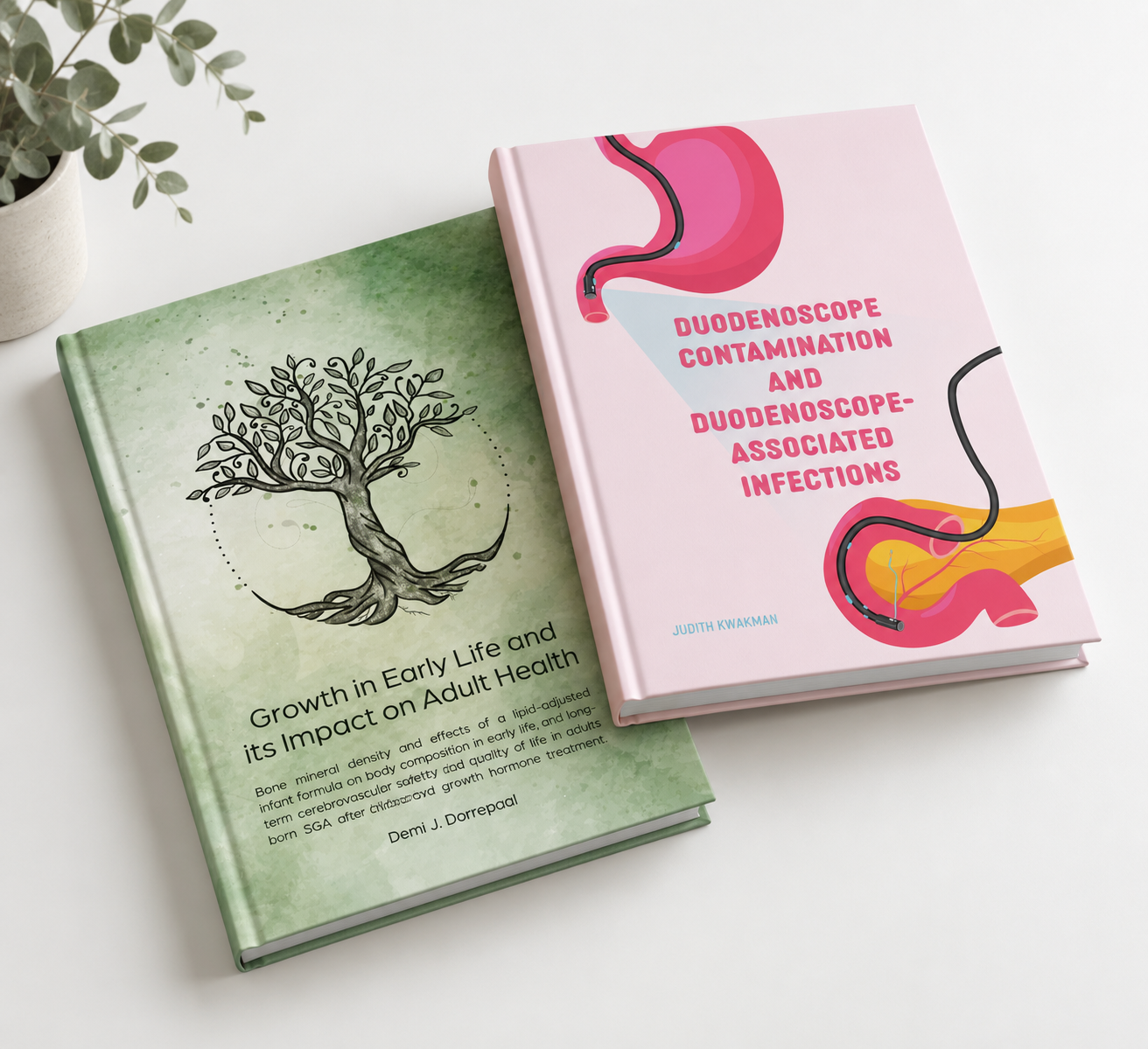 Twee boeken, een met een groene kaft over groei in het begin van het leven en de impact op volwassenheid, en een met een roze kaft over duodenoscopie besmettingen. Er ligt ook een keramieken plantpot met een groene plant en een witte achtergrond.
