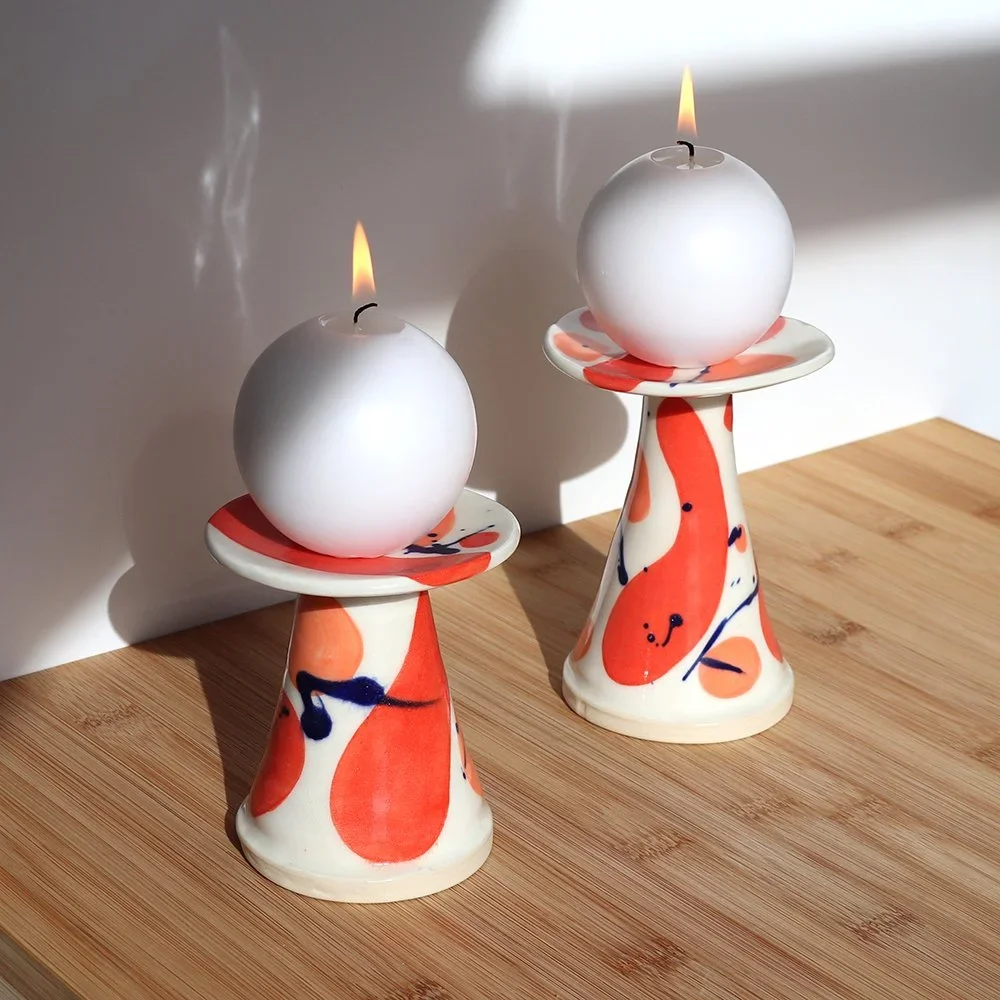 two handmade ceramic candleholders in orange and white colors