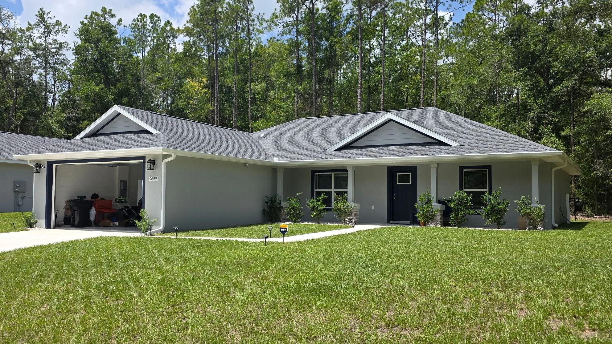 White seamless gutters installed on a gray home with a covered entry in Citrus Springs, Florida.