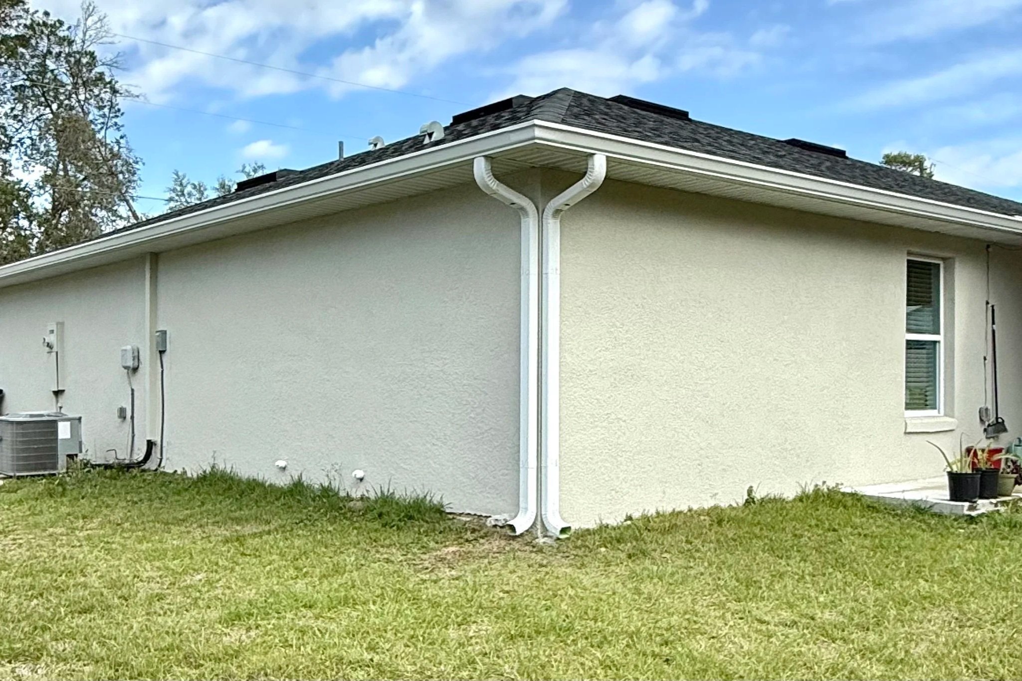 White seamless gutters and downspouts installed on a stucco home in Marion Oaks, Florida.