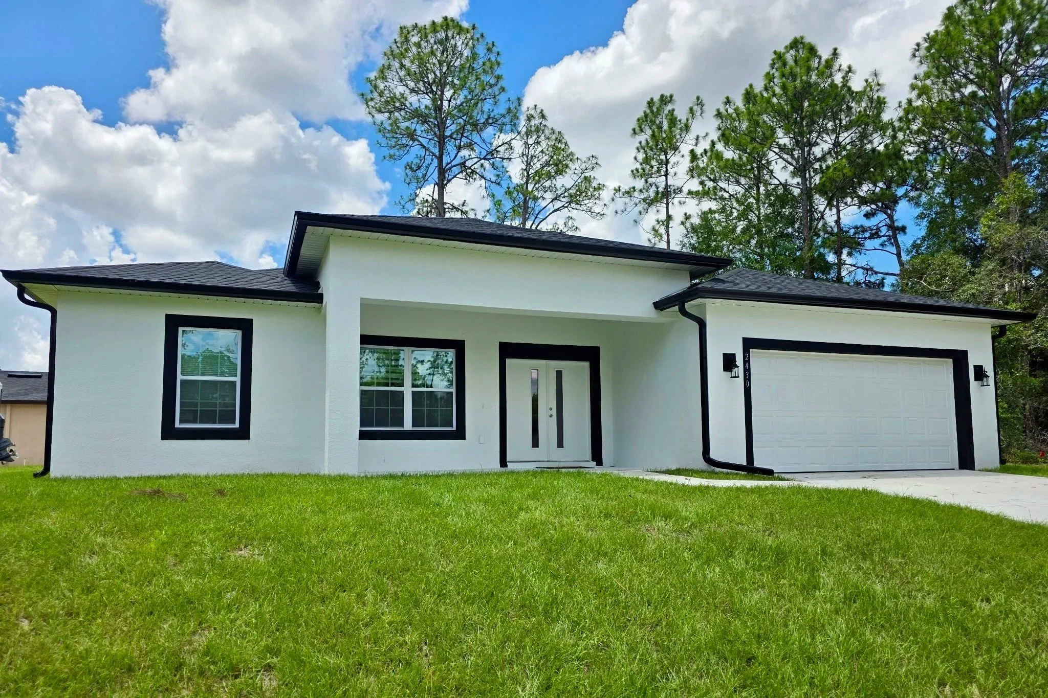 Black seamless gutters installed on a modern white home in Marion Oaks, Florida.