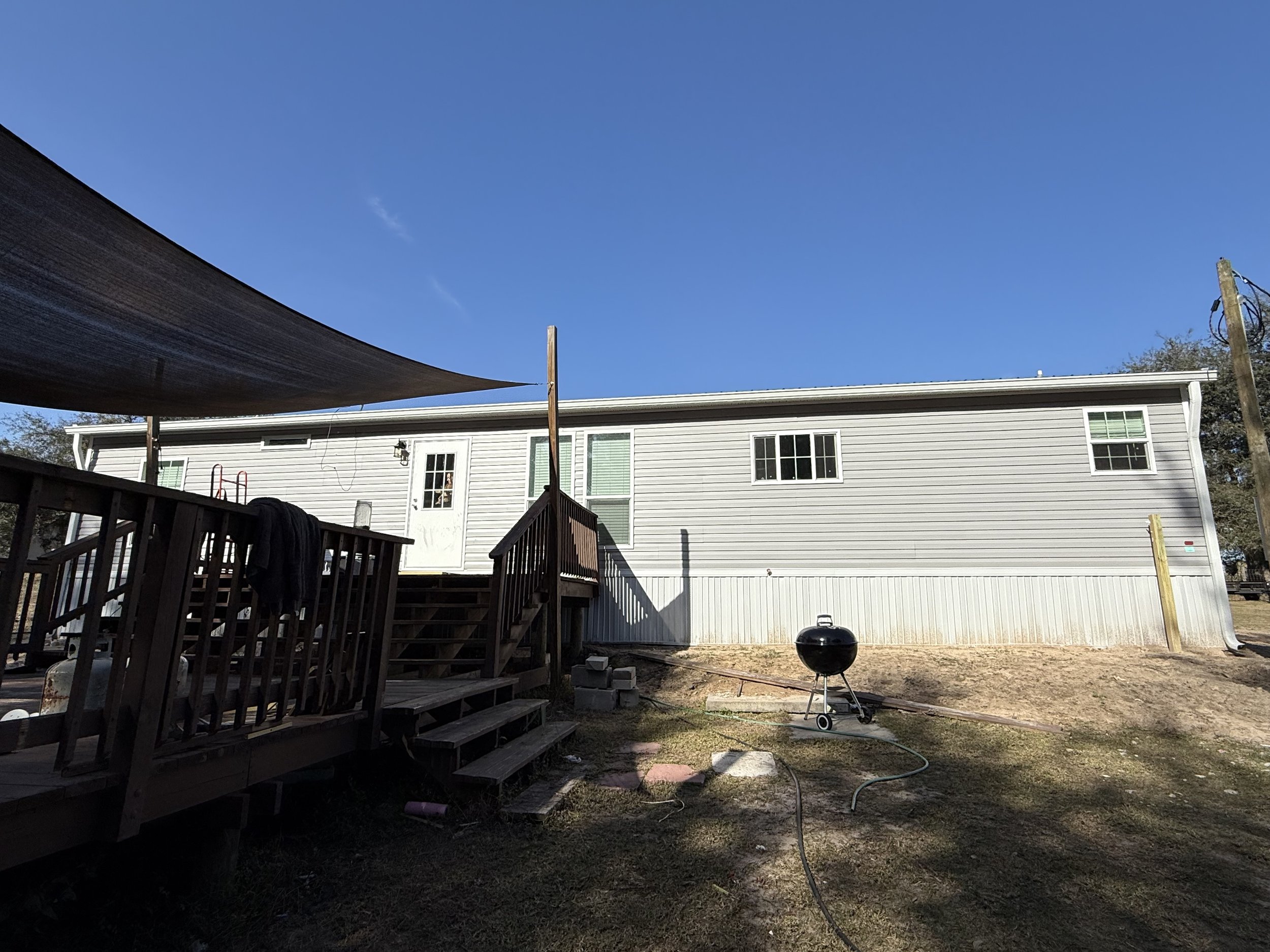 White seamless gutters and downspouts installed on rear of mobile home in Weirsdale, Florida