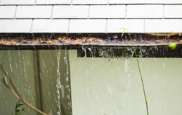 Clogged rain gutter overflowing during rainfall