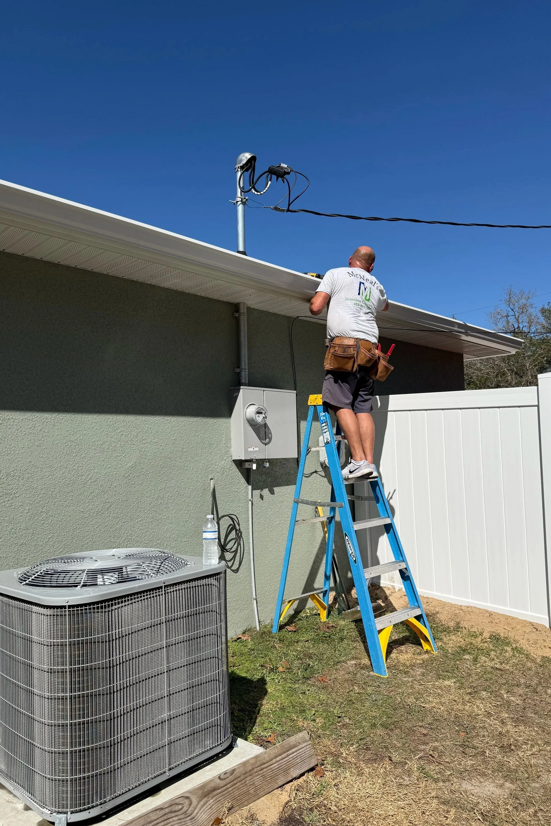 Danny installing seamless gutter from a ladder on home in Ocklawaha, Florida