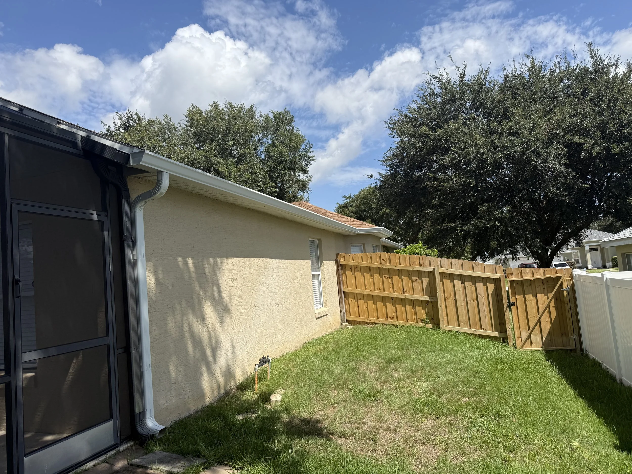 Side view of white seamless gutters and downspout installed on a home in Oakmont at Silver Lake, Leesburg, FL.