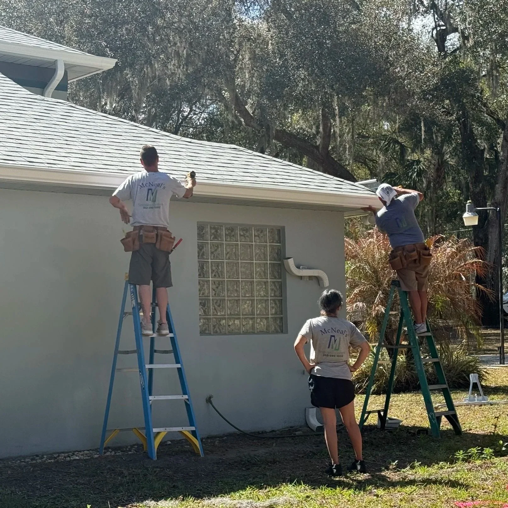 Danny McNeal installing seamless gutters with help from family on a residential home.