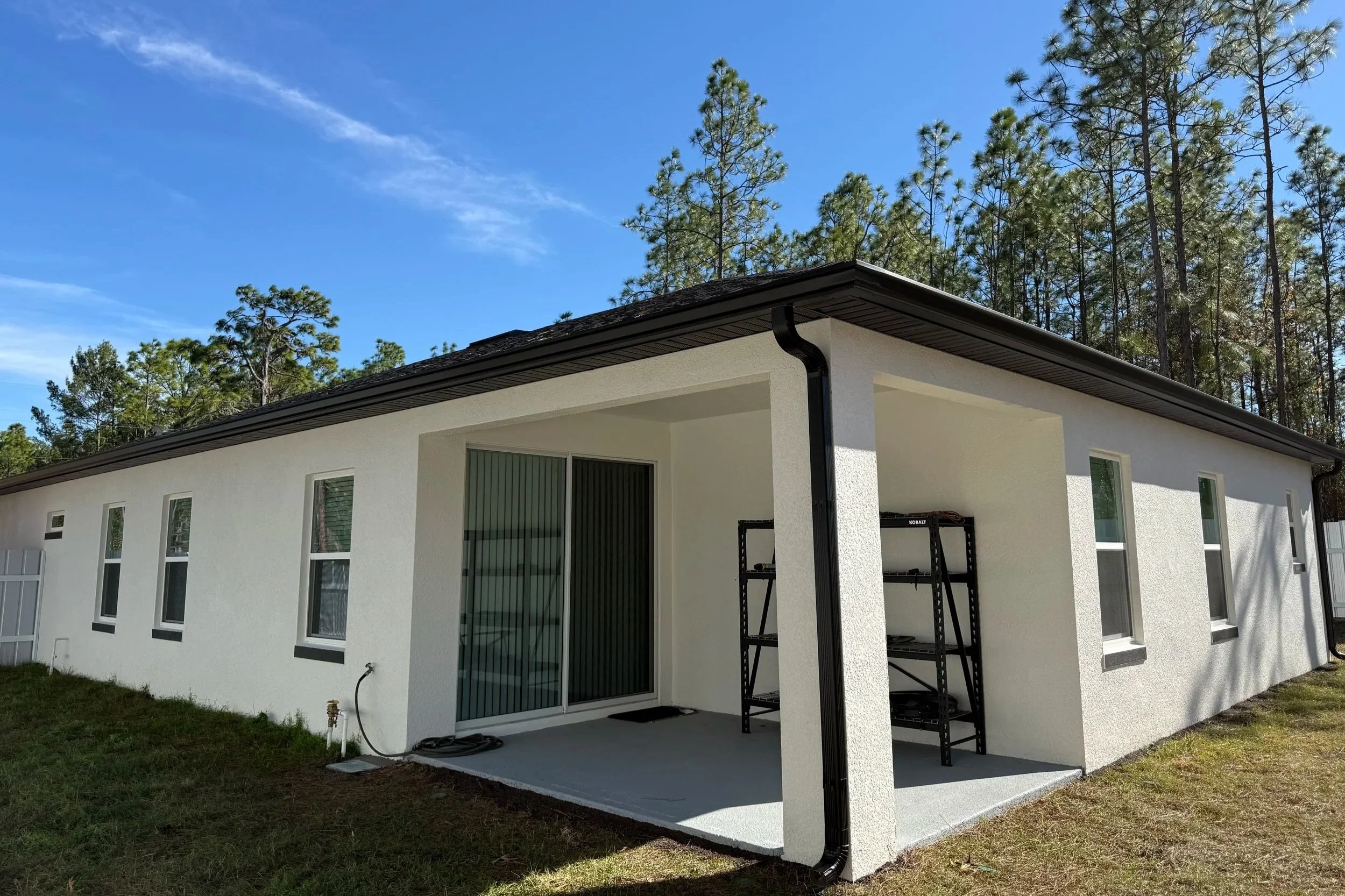 Black seamless gutters installed around the roofline and covered patio of a home in Marion Oaks, Florida.