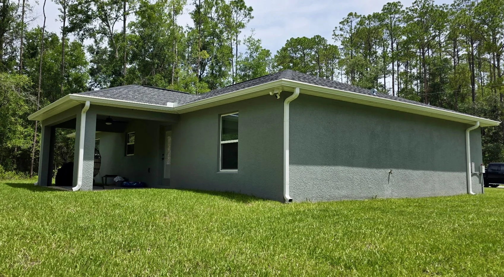 White seamless gutters and downspouts installed on a gray home in Citrus Springs, Florida.