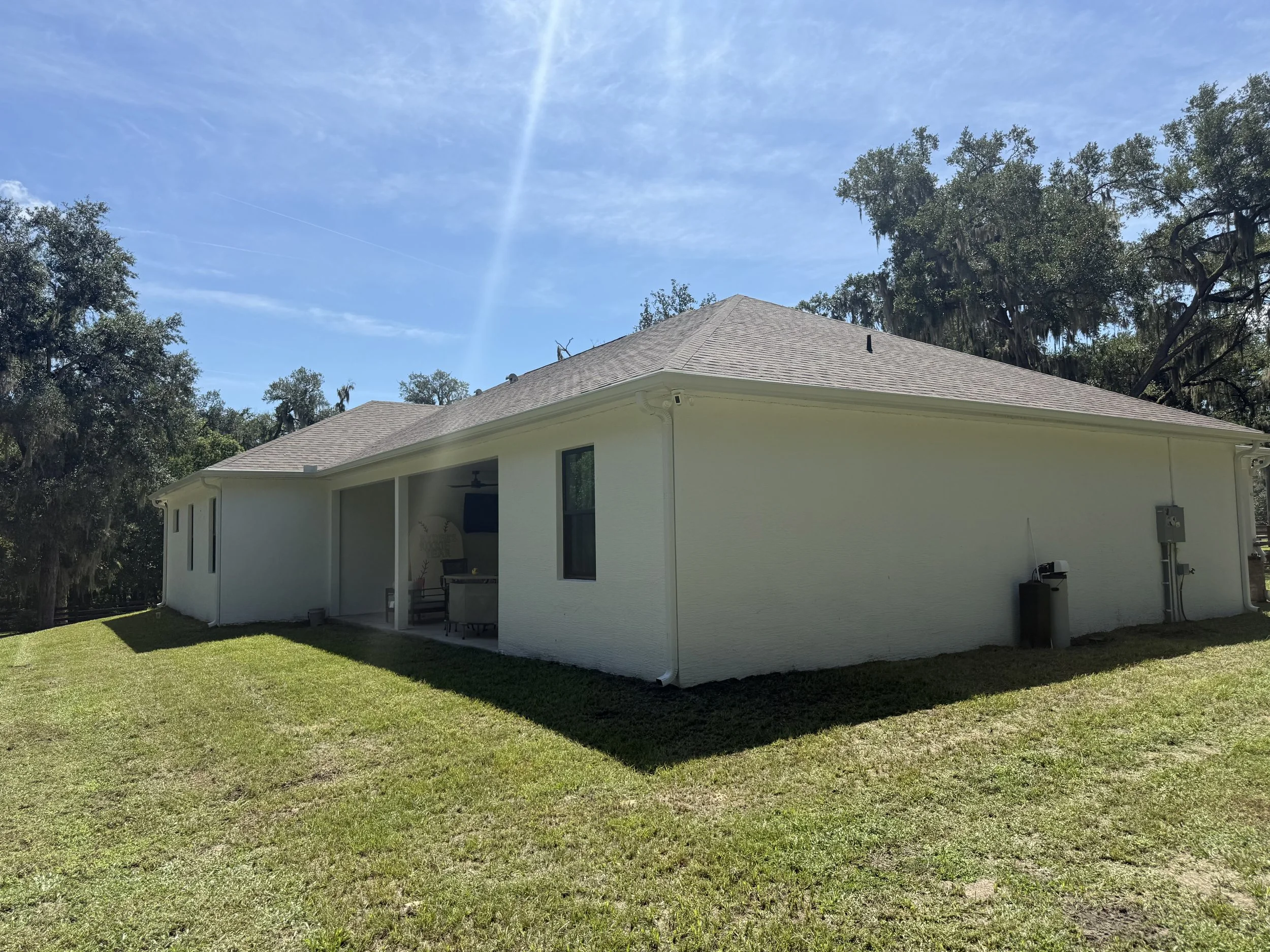 Side and rear roofline featuring new white seamless gutters on a residential property in Fruitland Park, FL.