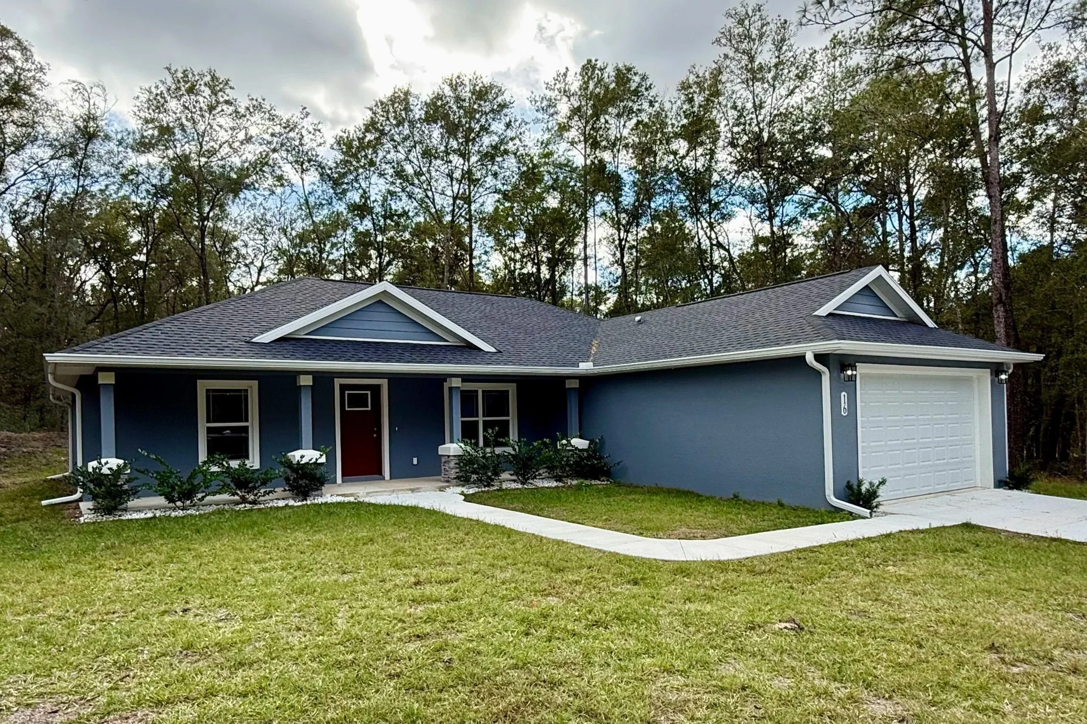White seamless gutters and downspouts installed on a blue home in Citrus Springs, Florida.