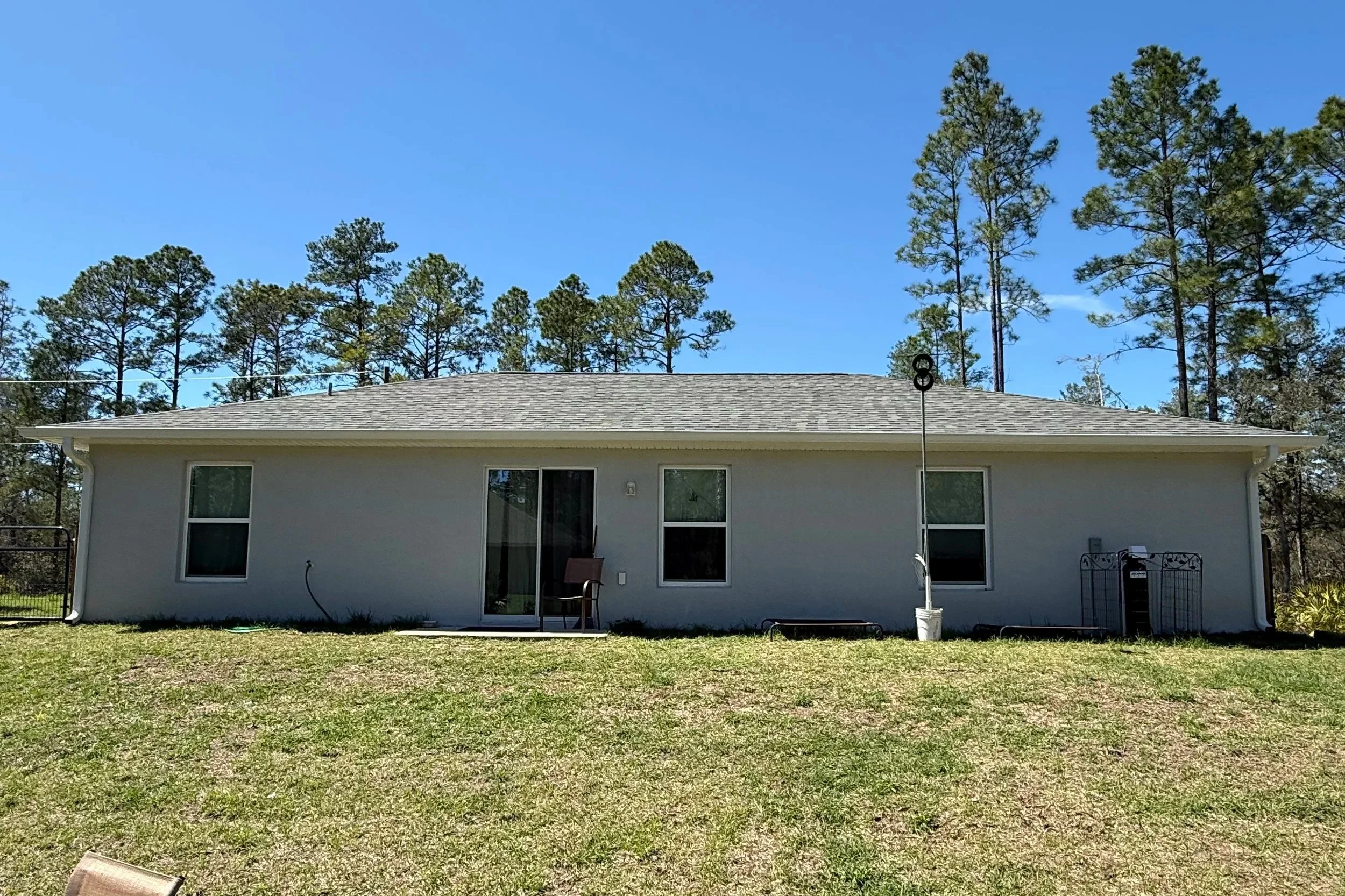 White seamless gutter and downspout system installed on gray home in Ocklawaha, Florida