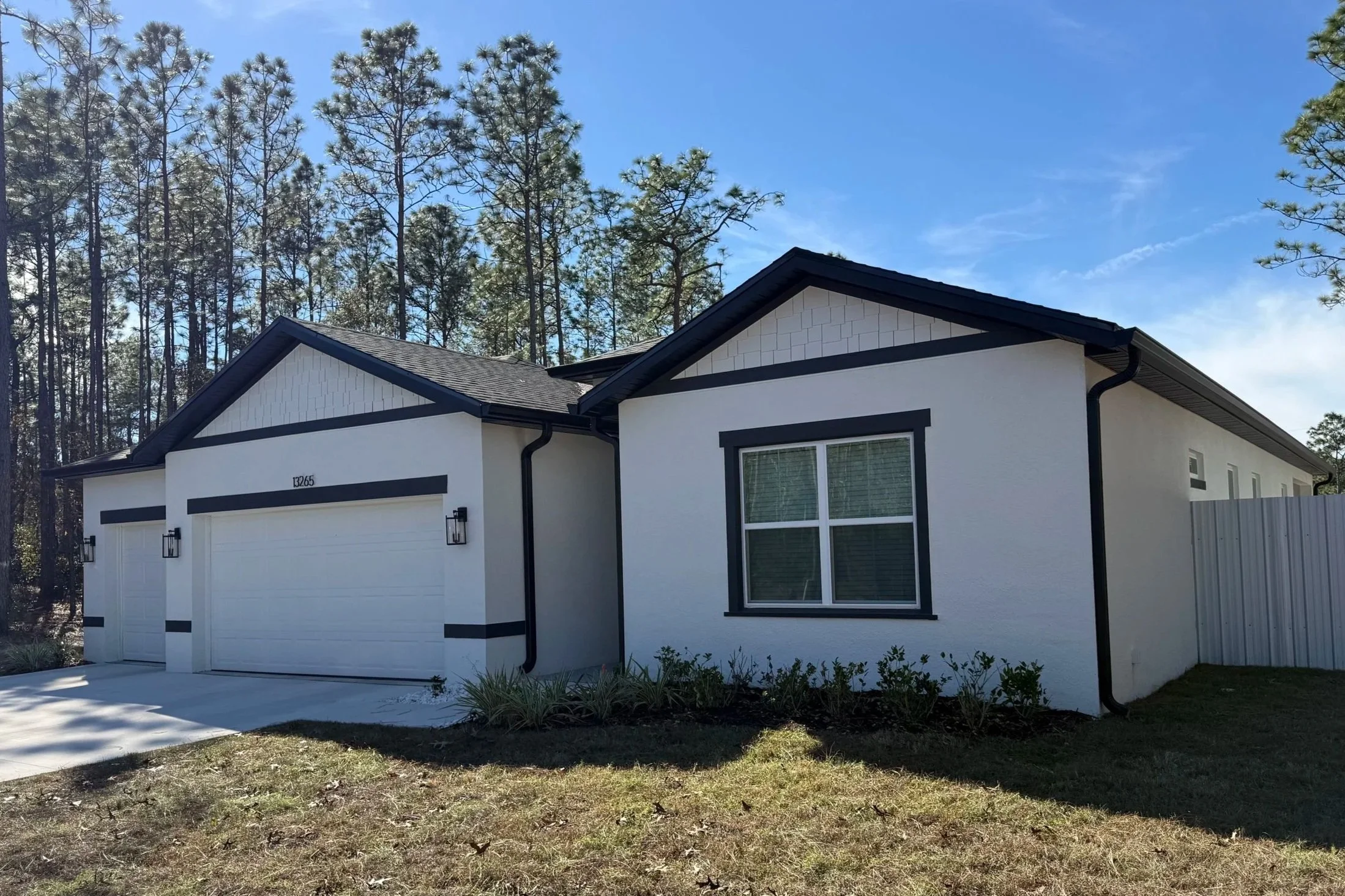 Black seamless gutters and downspouts installed on a white home in Marion Oaks, Florida.