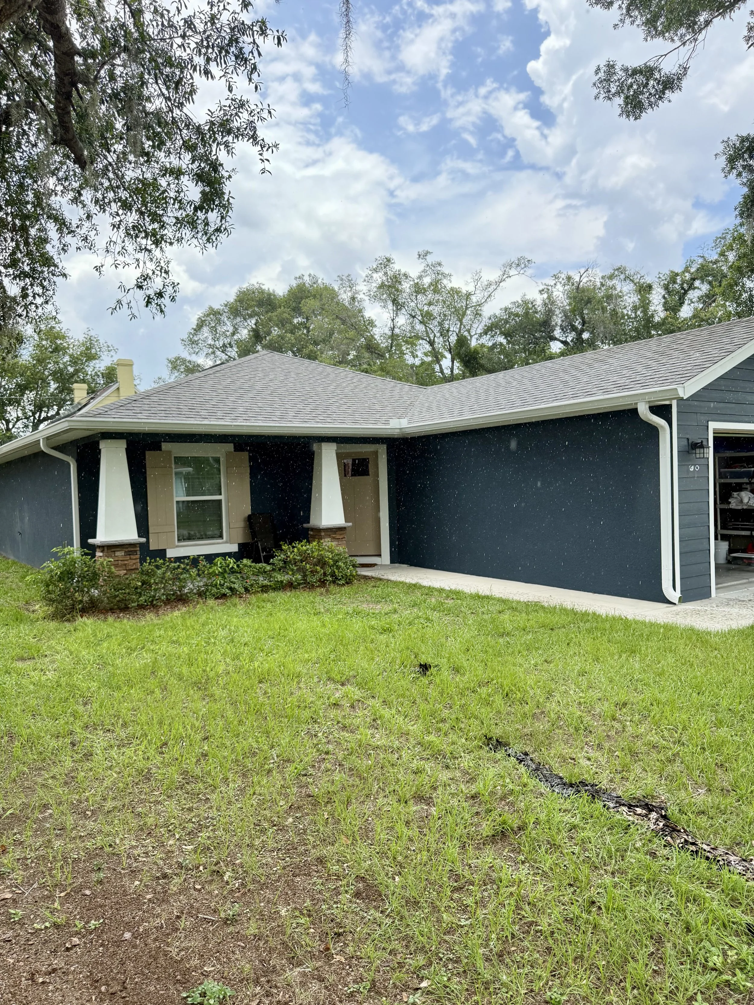 White seamless gutters and downspouts installed on blue home in Eustis, Florida