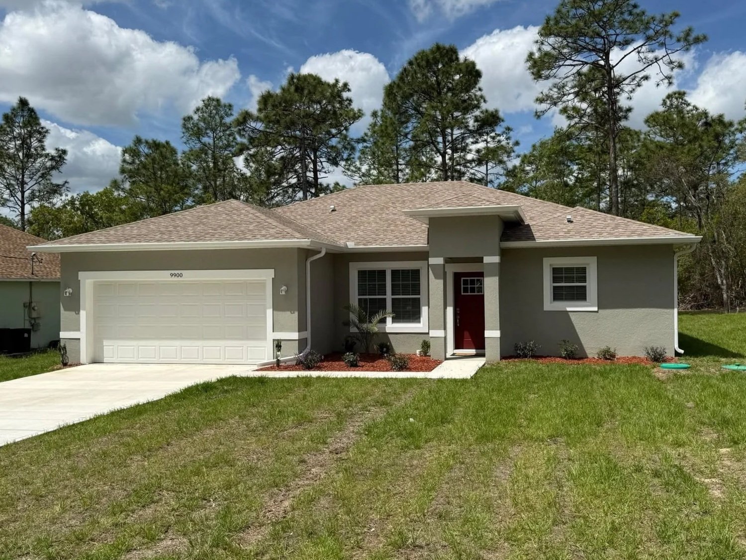 Front view of a Florida home with new white seamless gutters and downspouts installed by McNeal’s Seamless Gutters LLC, protecting the roofline, entryway, and landscaping