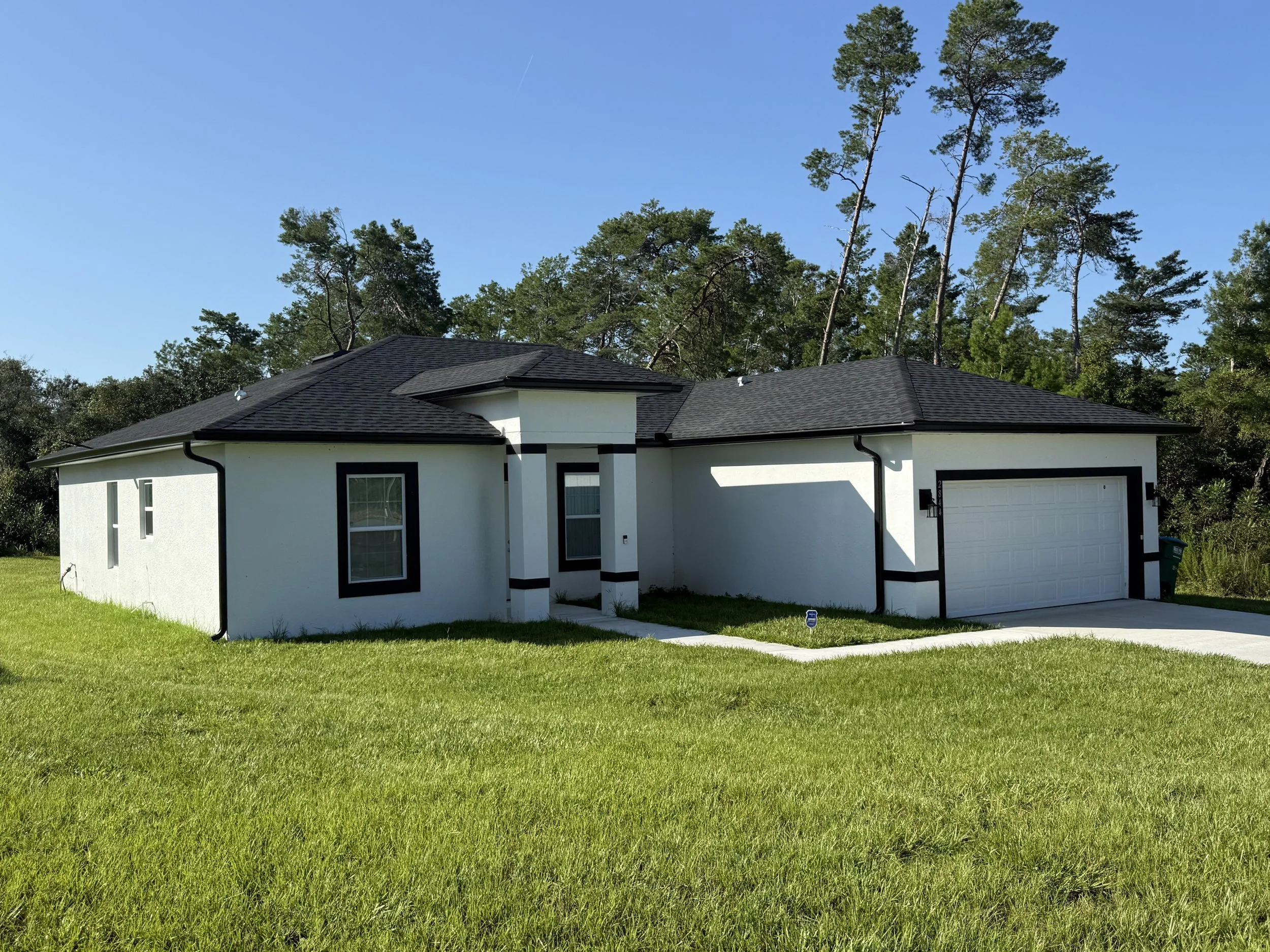 Black seamless gutters and downspouts installed on a white home in Marion Oaks, Ocala, Florida.