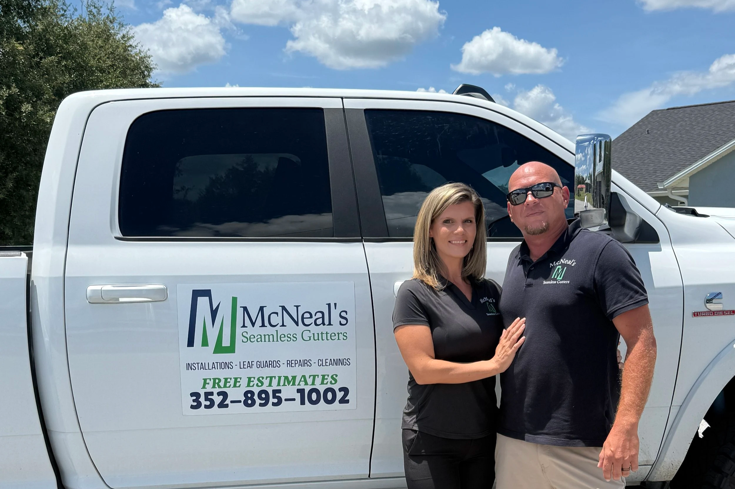 Danny and Danielle McNeal, owners of McNeal’s Seamless Gutters, standing beside their company truck.