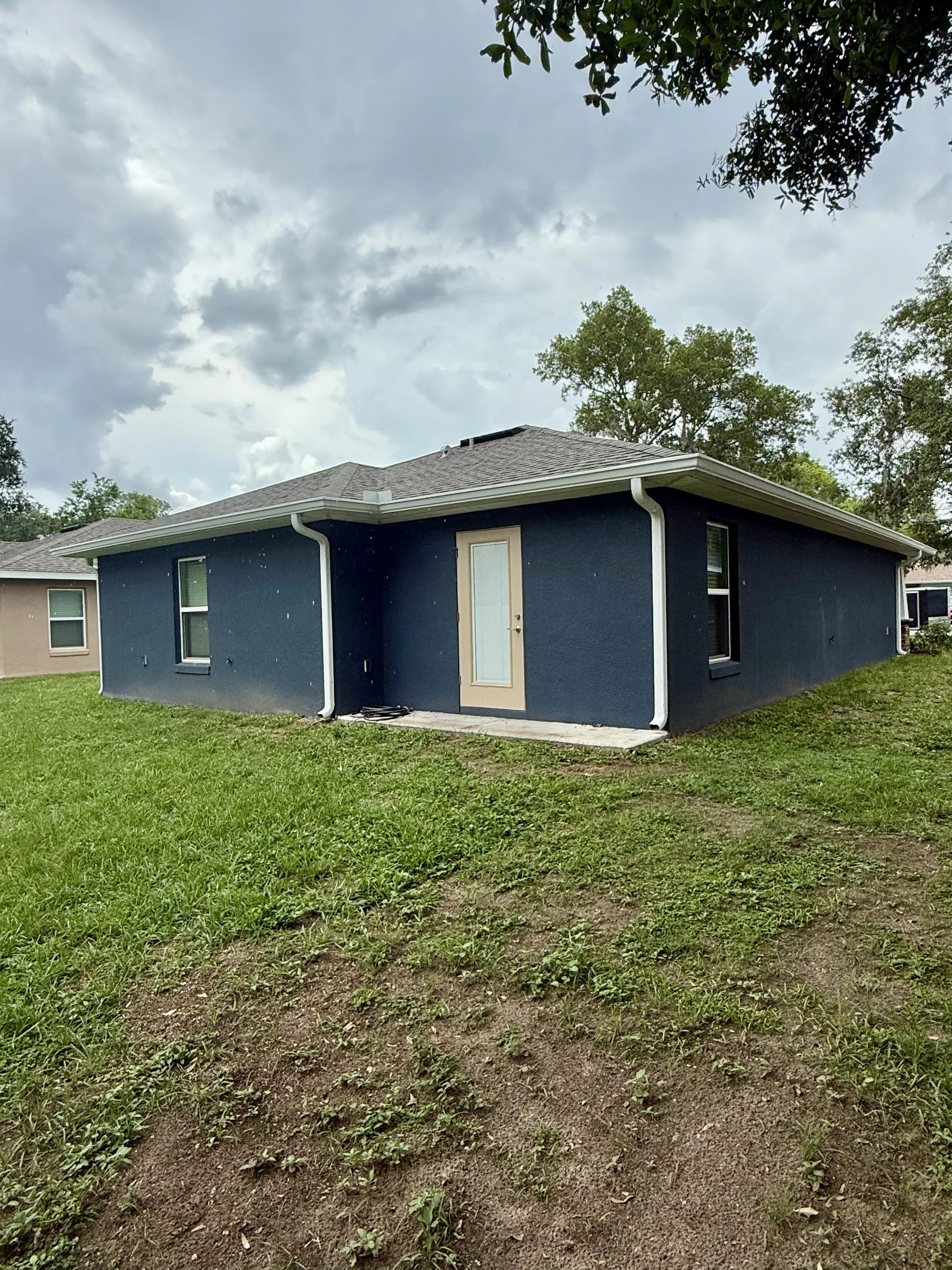 White seamless gutters and downspouts installed on blue home in Eustis, Florida