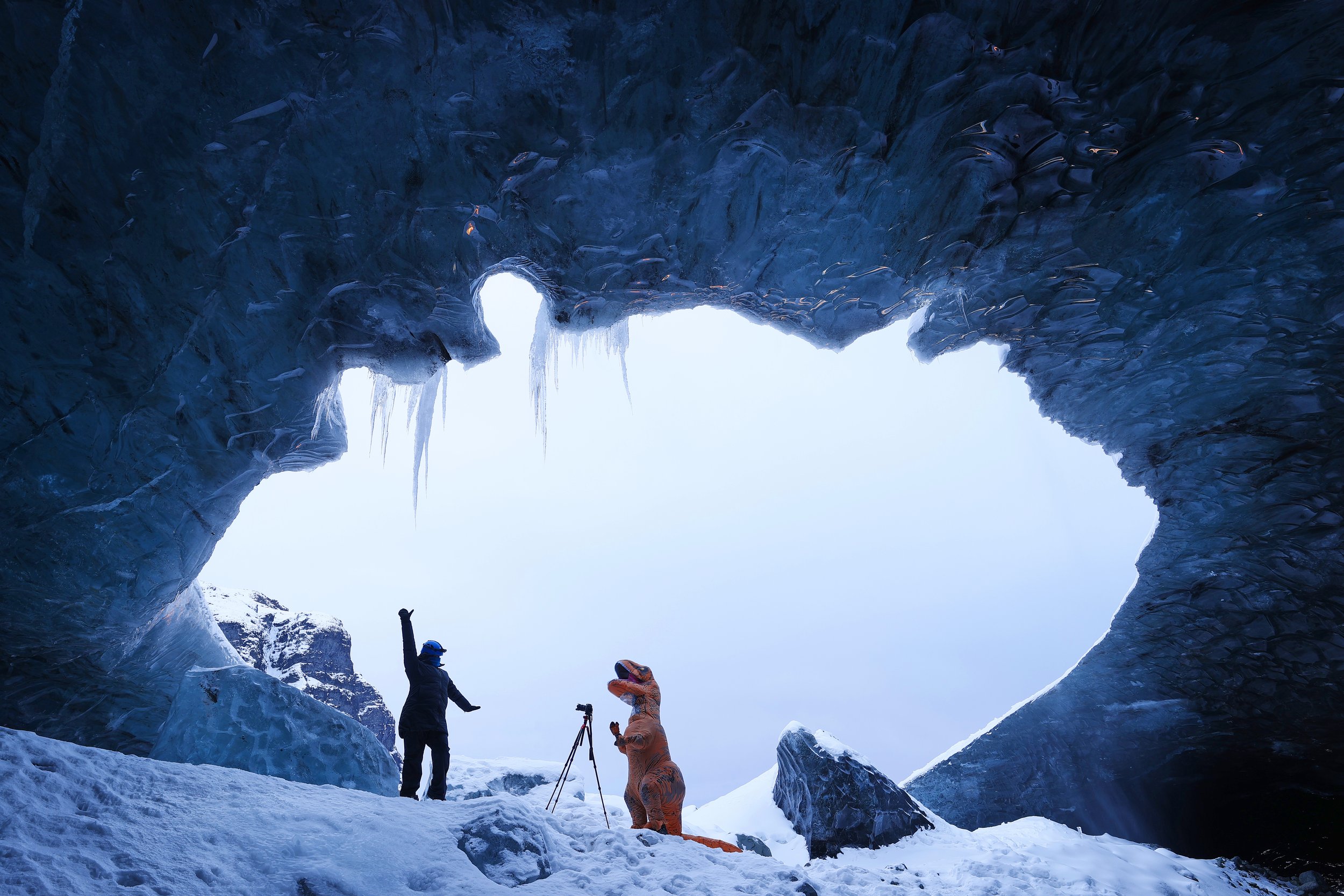 Person and dinosaur, T-Rex costume inside ice cave in Iceland.