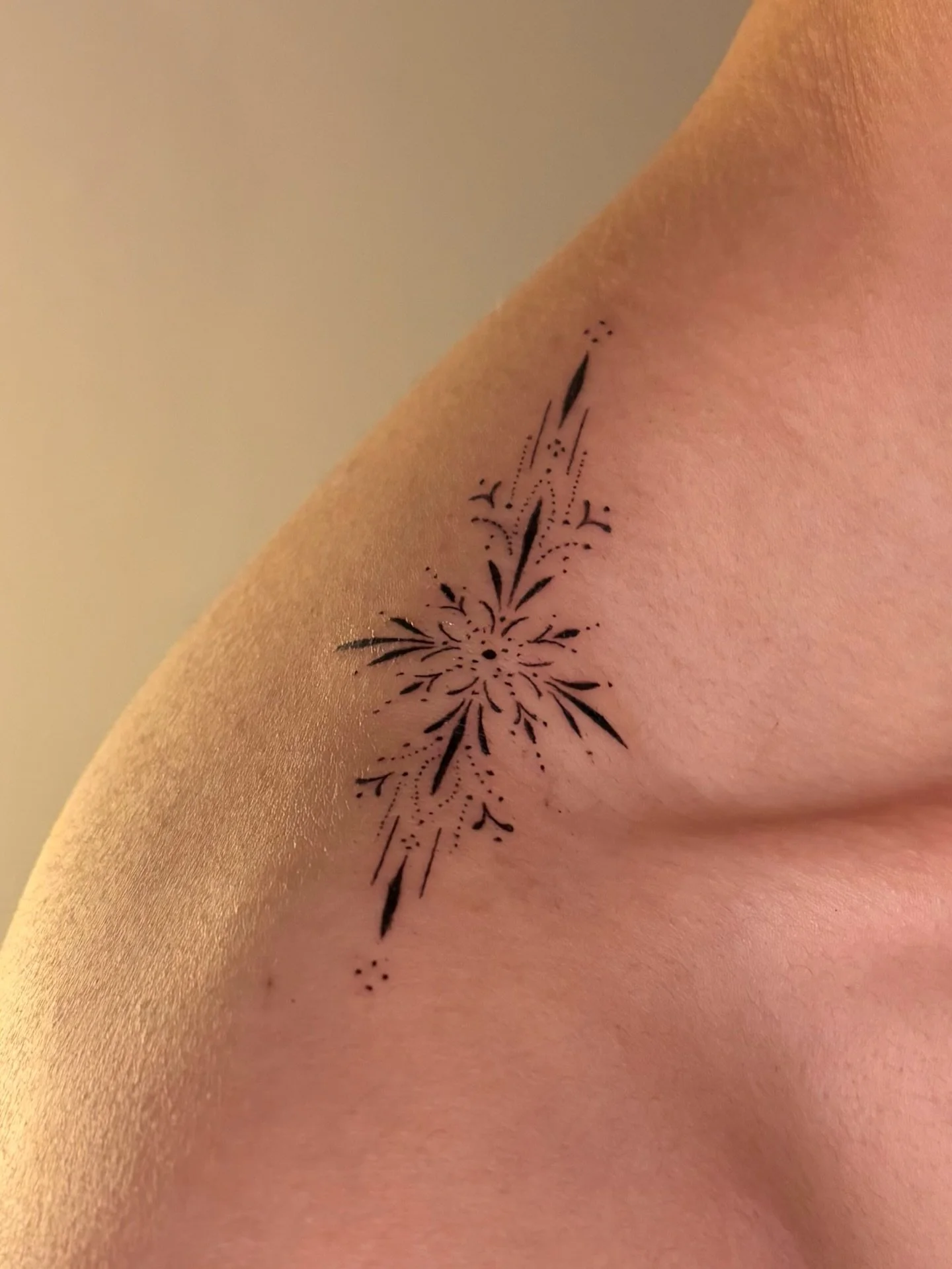 Close-up of a black floral and botanical tattoo on the upper chest and shoulder