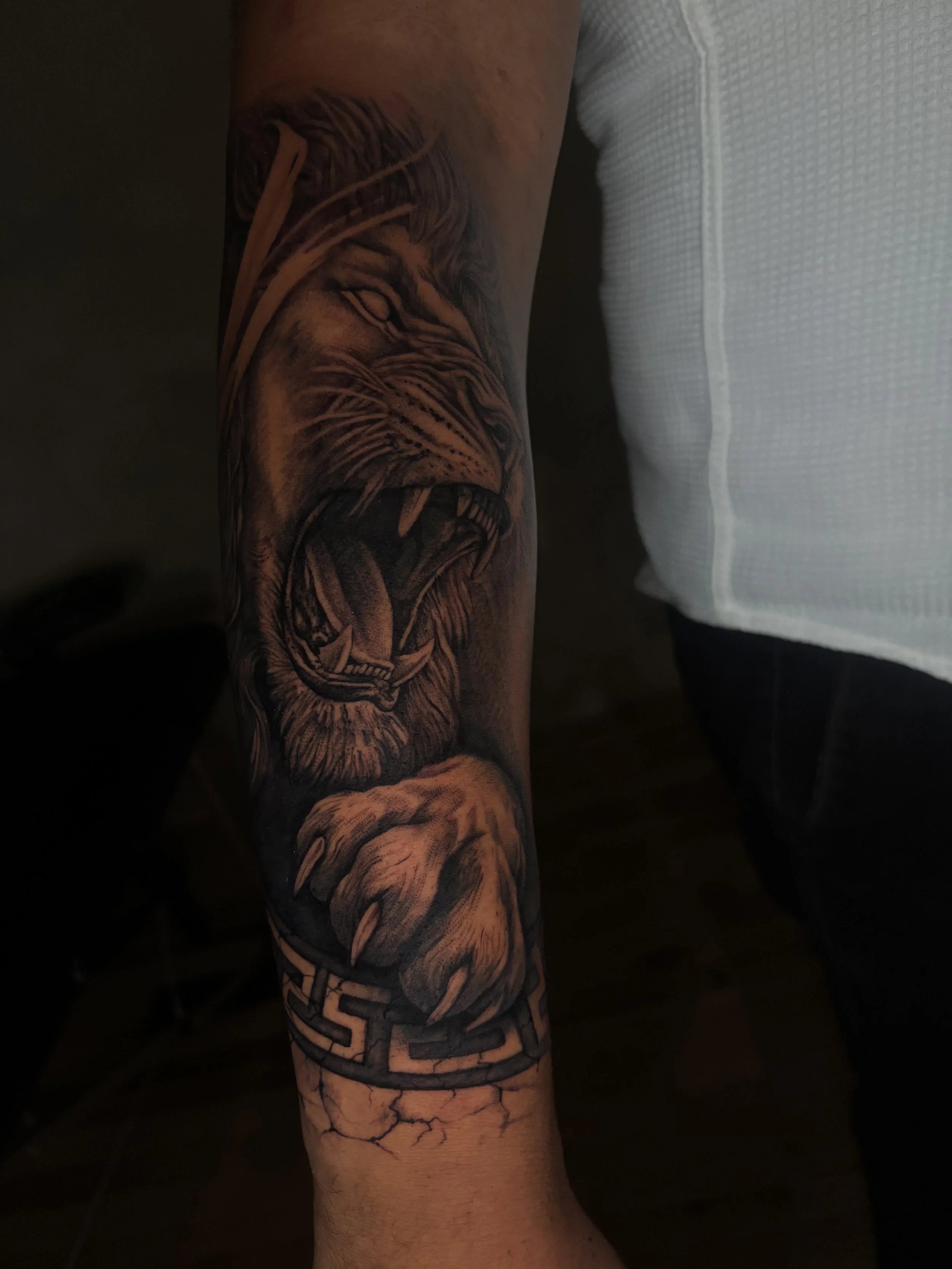 Tattoo of a roaring lion's face on the person's forearm, with the tiger's mane extending down the arm, and a geometric pattern below.