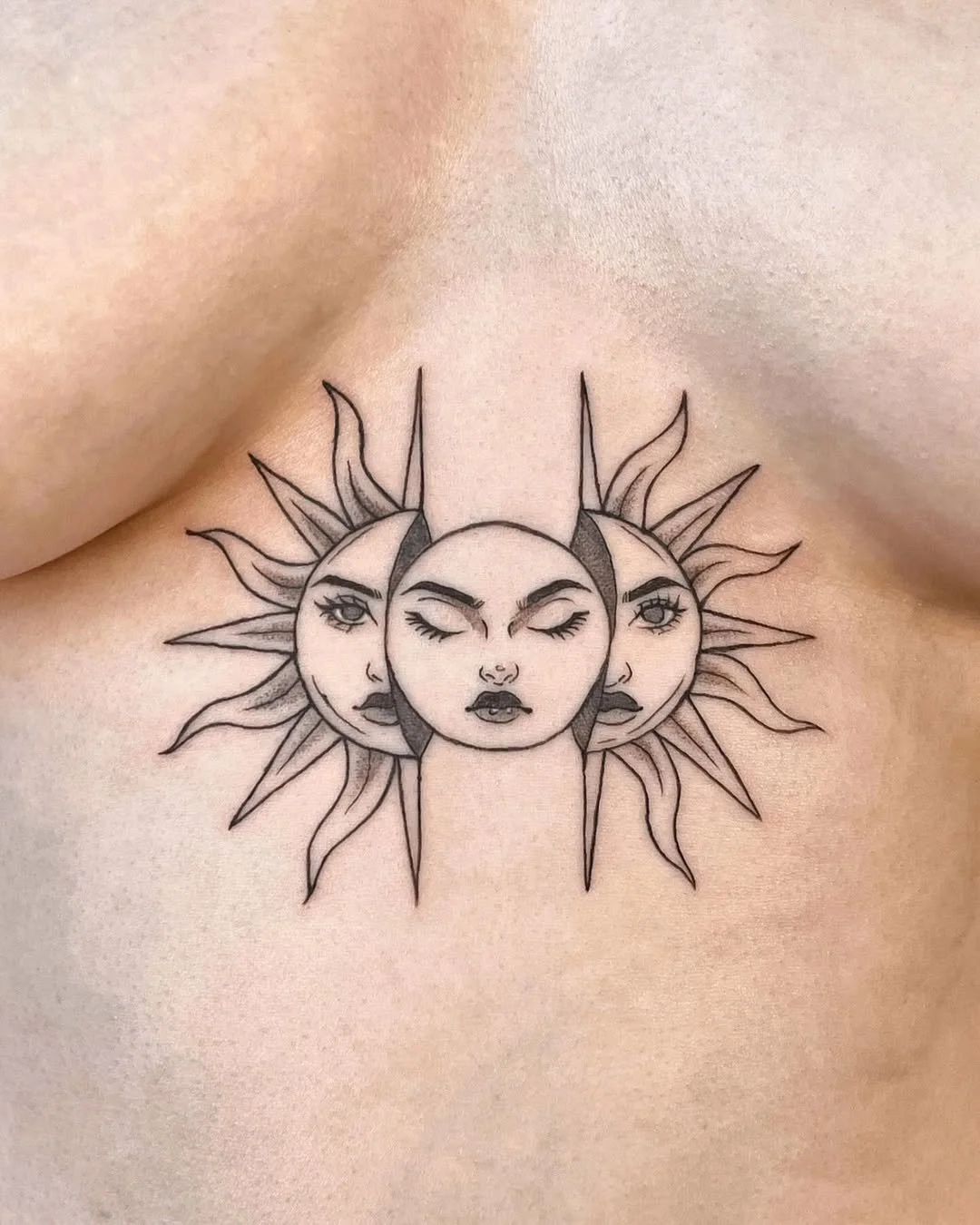 Tattoo of three women's faces surrounded by sun rays on skin.