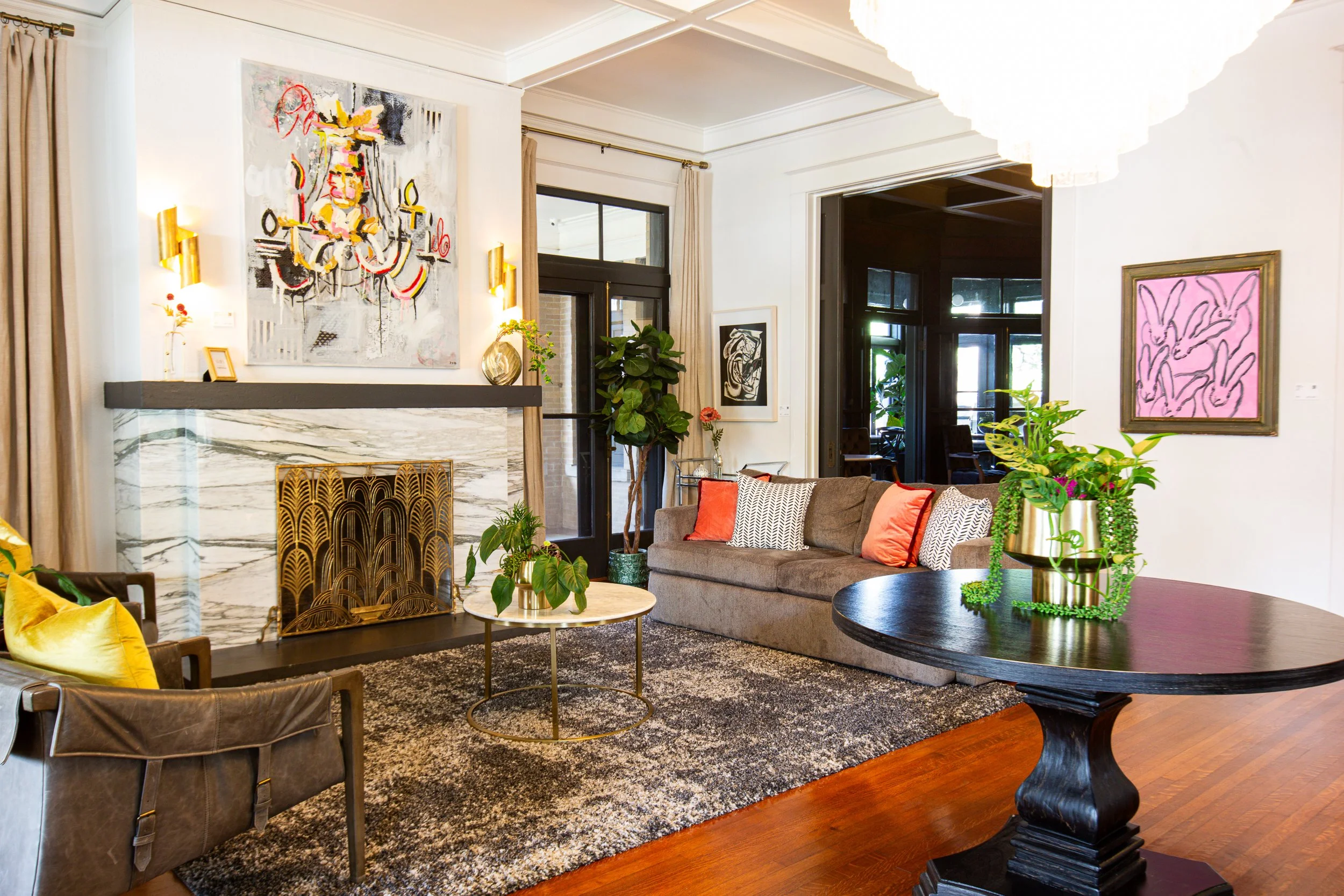 Living room with a sofa, accent chairs, artwork, and plants.