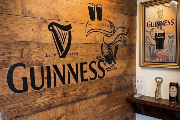 Interior wall with Guinness logo, rainbow, and a pint glass illustration, surrounded by a mirror and decorative items.