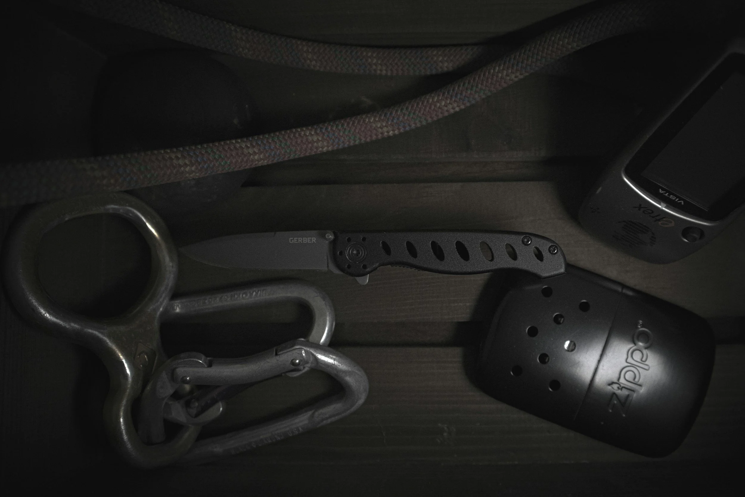 A collection of fitness equipment including a kettlebell, a multi-position pull-up bar, and two dumbbells, on a dark floor.