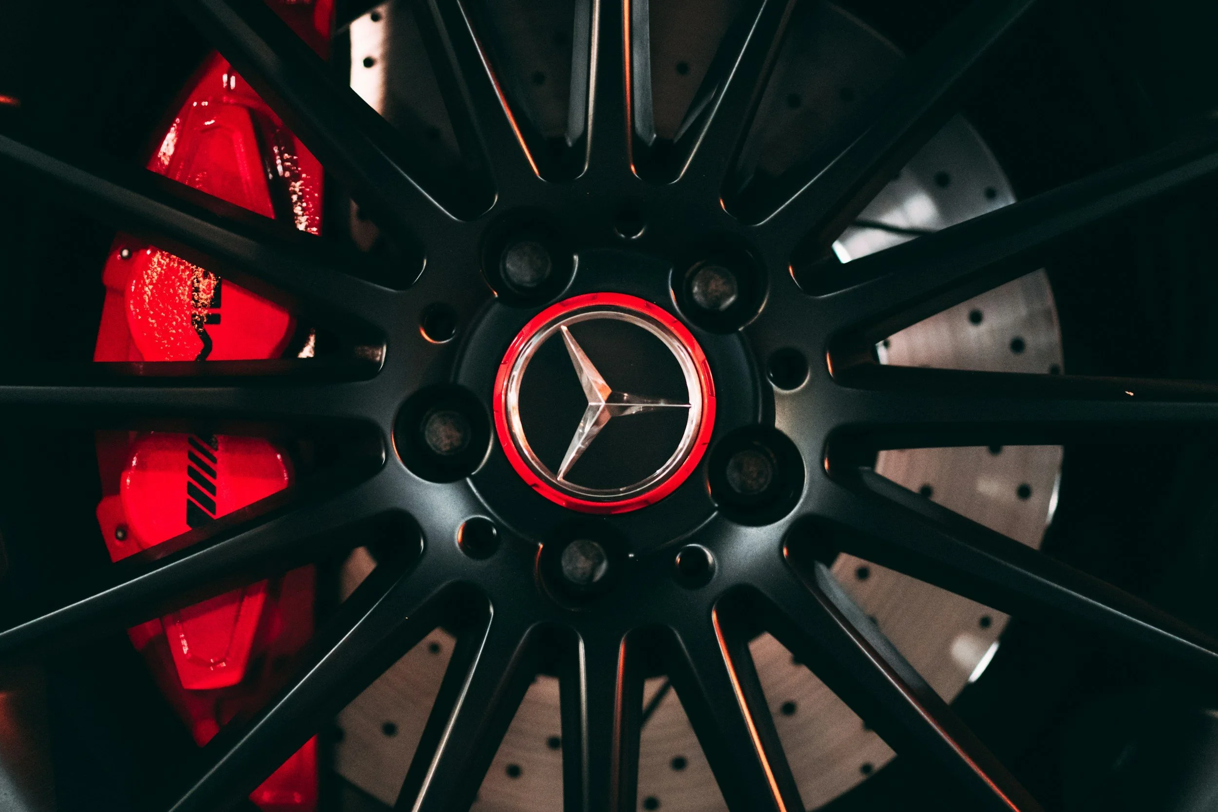 Close-up of a black Mercedes-Benz wheel with a red brake caliper behind it.