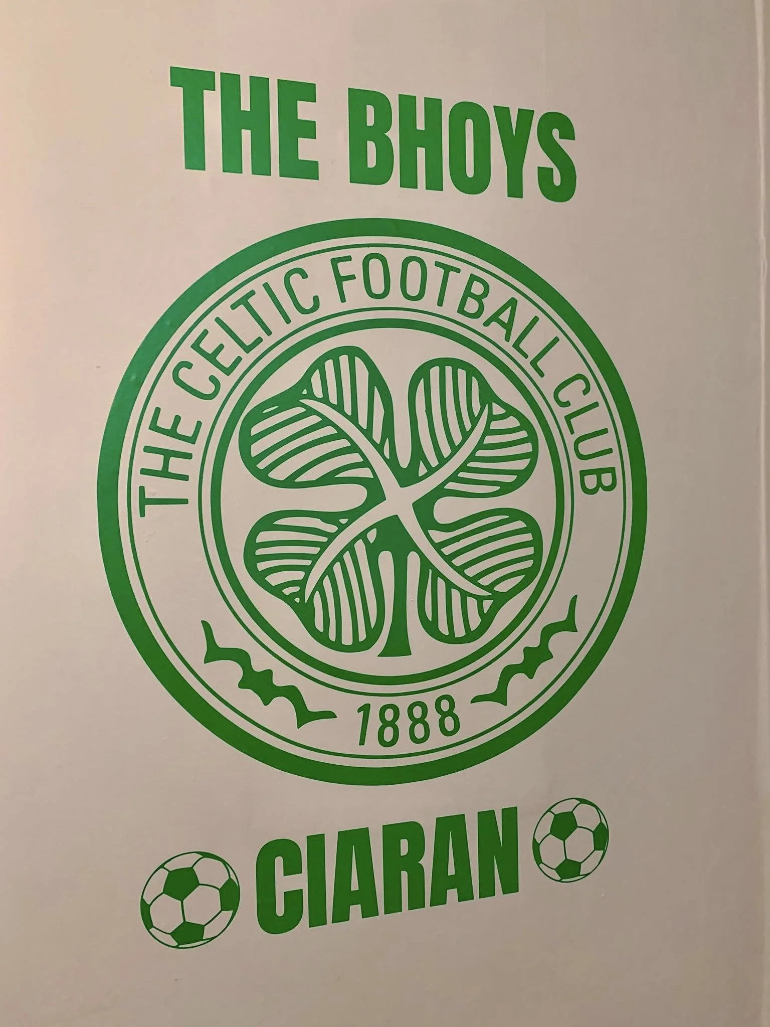Green logo for Celtic Football Club with a four-leaf clover in the center, encircled by the words 'The Celtic Football Club 1888'. The words 'The Bhoys' appear above the logo, and 'Ciaran' with two soccer ball icons are below.