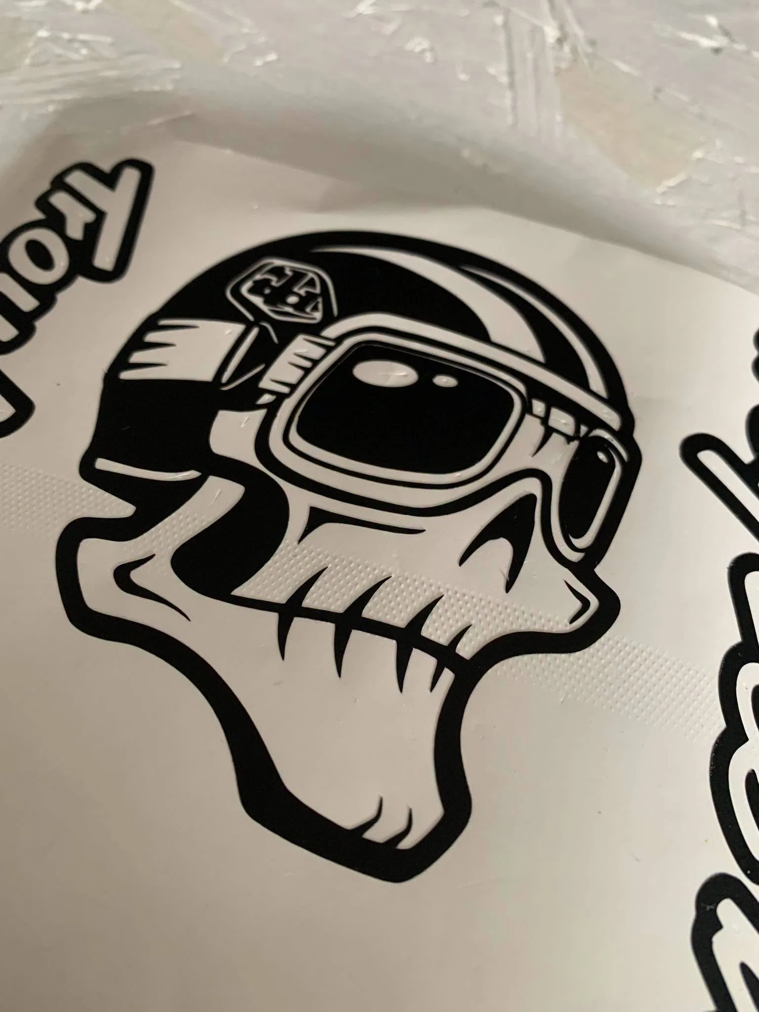 Close-up image of a black and white dinosaur design with a helmet on its head, printed on a white textured surface.