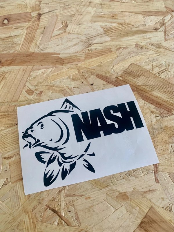 A black and white sticker with a fish illustration and the word "NASH" written in bold capital letters on a wooden surface.