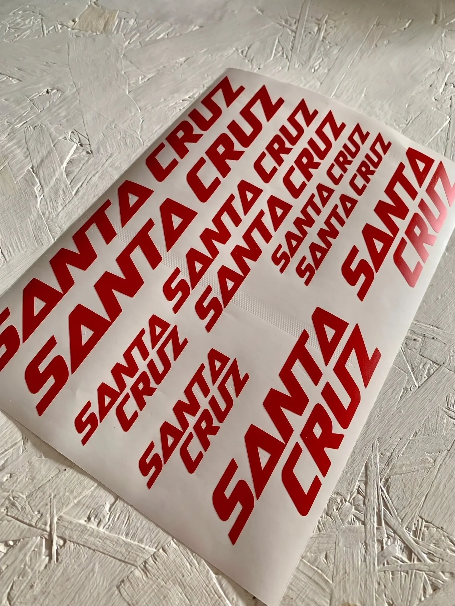 A sheet with multiple red 'CRUSH' labels on a white background, placed on a white, textured wooden surface.