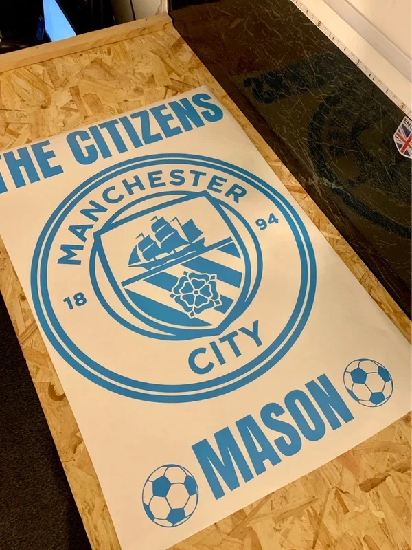Poster on a wooden table for Manchester City football club and Mason