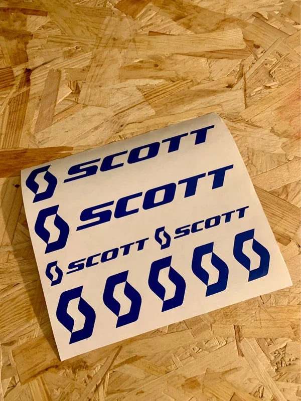 Sheet of stickers with the word 'SCOTT' and a stylized 'S' logo in blue, on a wooden surface.