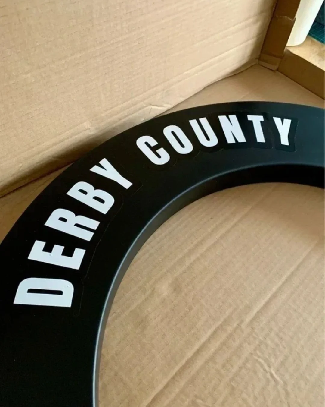 A black circular sign with white bold letters that read 'DEREY COUNTY'.