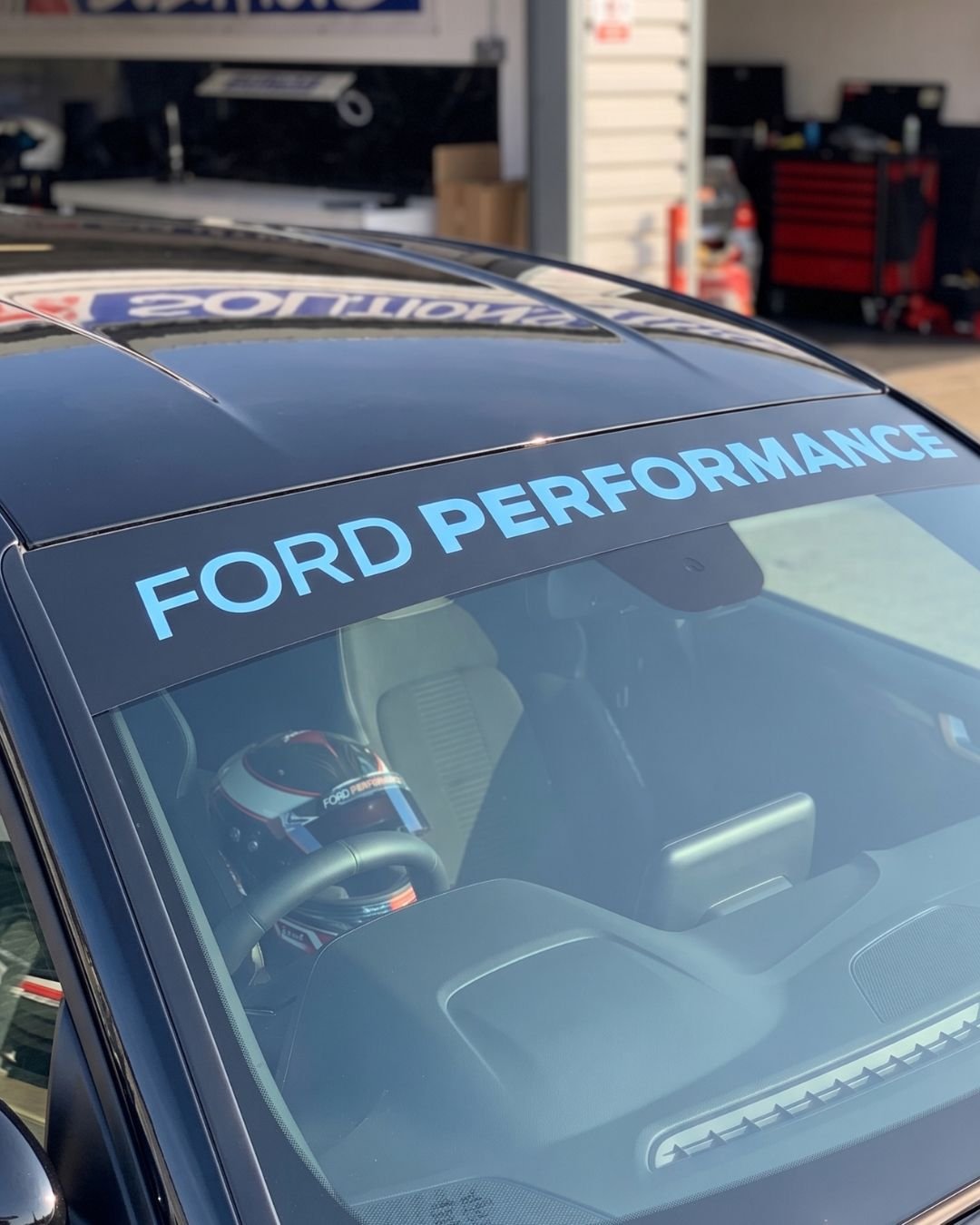 Front windshield of a black Ford vehicle with a blue sticker that reads 'FORD PERFORMANCE'.