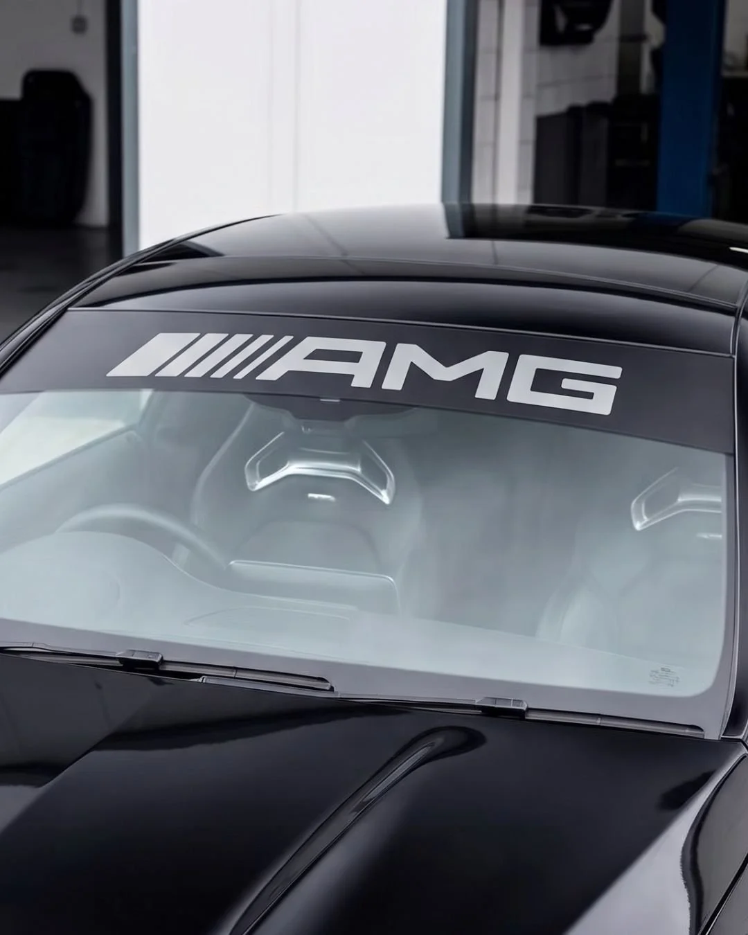 Close-up of a black Mercedes-AMG car with a large AMG logo on the windshield.