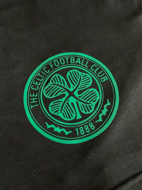 Close-up of the Celtic Football Club logo in green on black fabric.