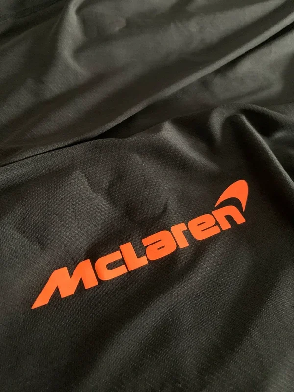 Close-up of a black fabric with the McLaren logo in orange.