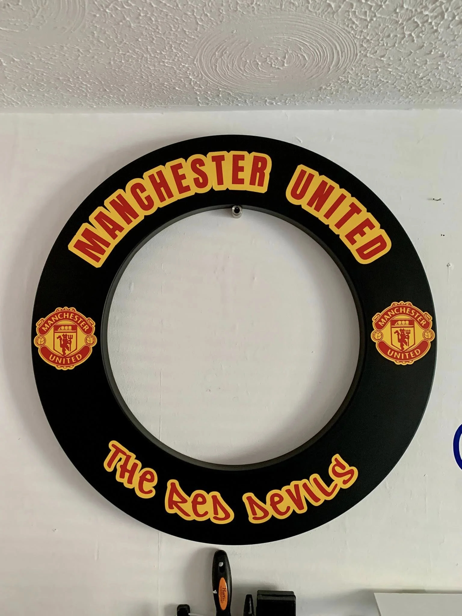 A circular sign with the text "Manchester United" and "The Red Devils" in red and yellow colors.
