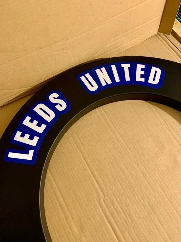 Close-up of a circular sign with a black border and blue background, displaying the words "LEEDS UNITED" in white, uppercase letters.