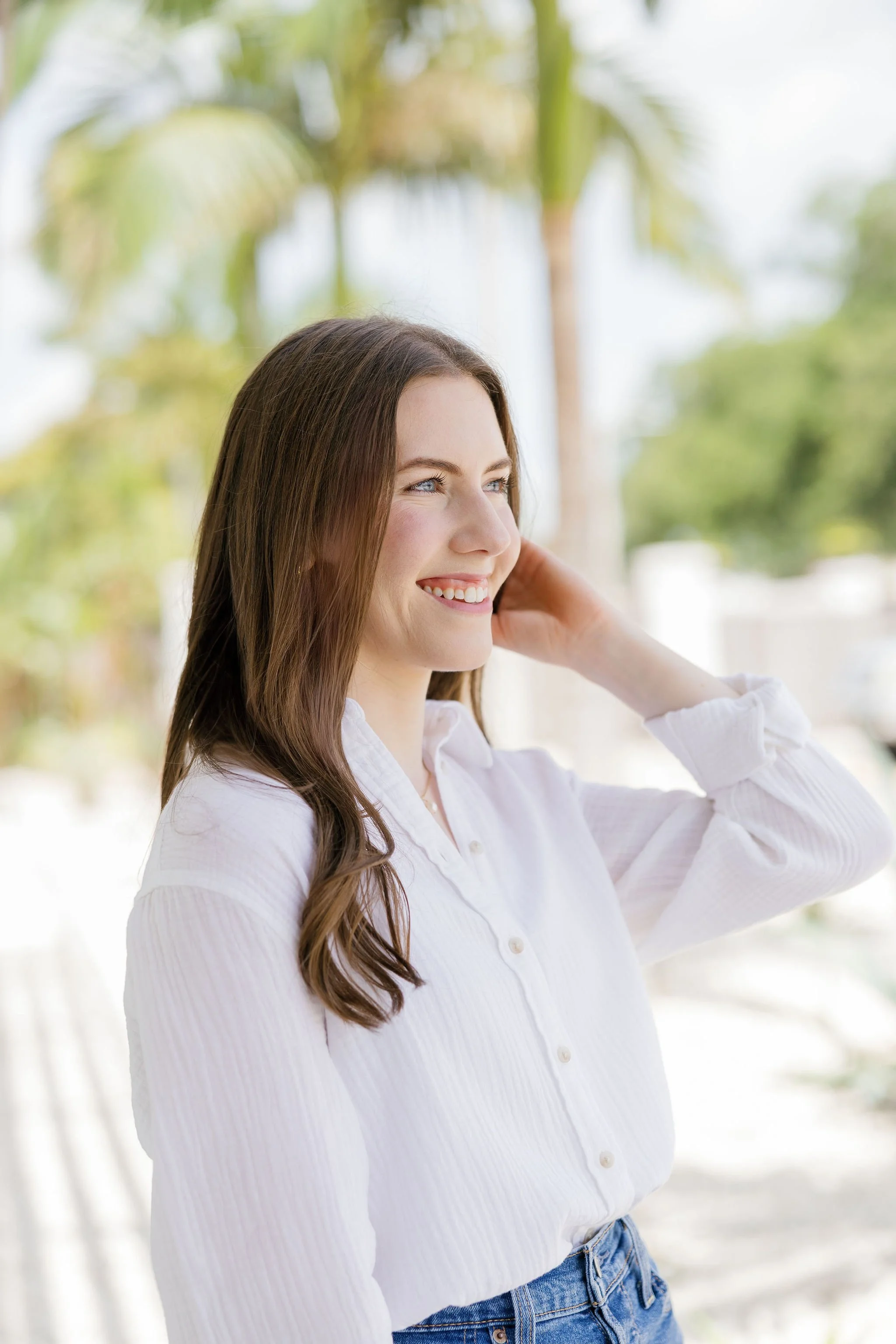 Rachael Mayorga of Sunrise Social Co. standing outside by palm trees smiling off into the distance.