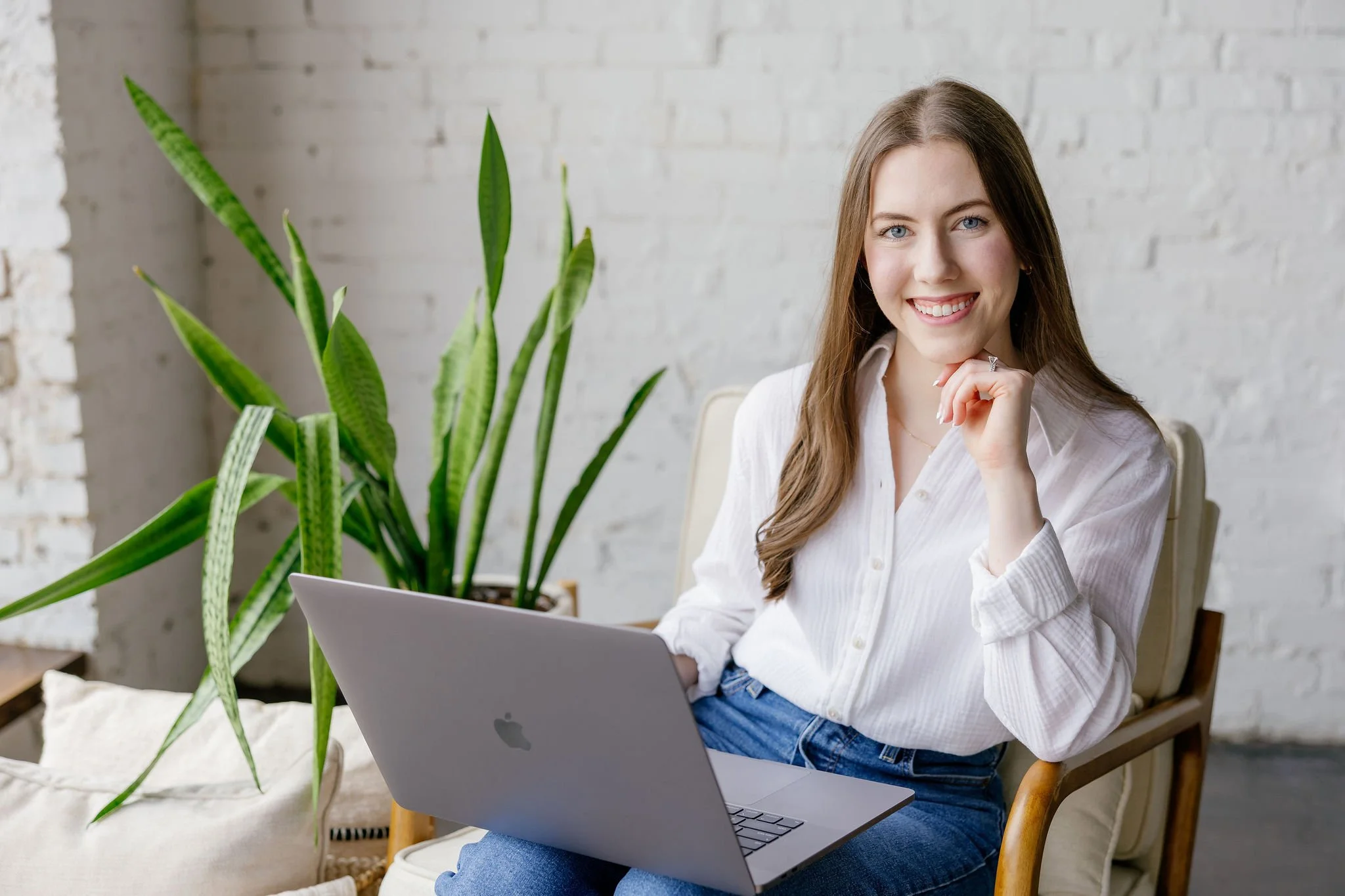 Rachael Mayorga of Sunrise Social Co. smiling and working on her laptop while sitting in a chair.