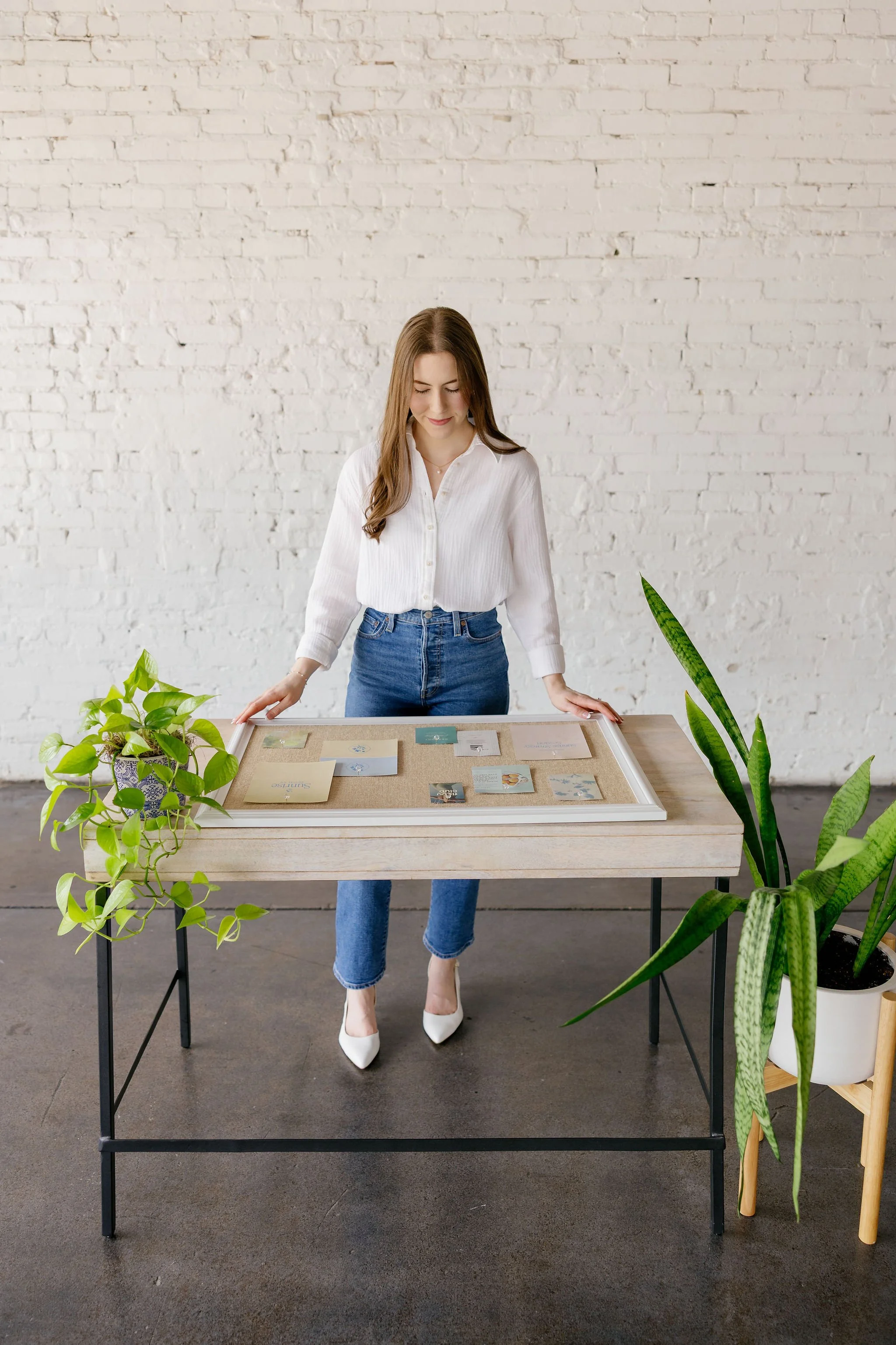 Rachael Mayorga of Sunrise Social Co. standing at a desk while looking down at a marketing moodboard.