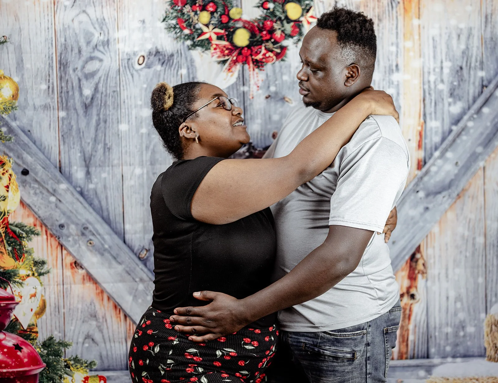 A couple dancing closely, with a festive Christmas wreath and decorated tree in the background.