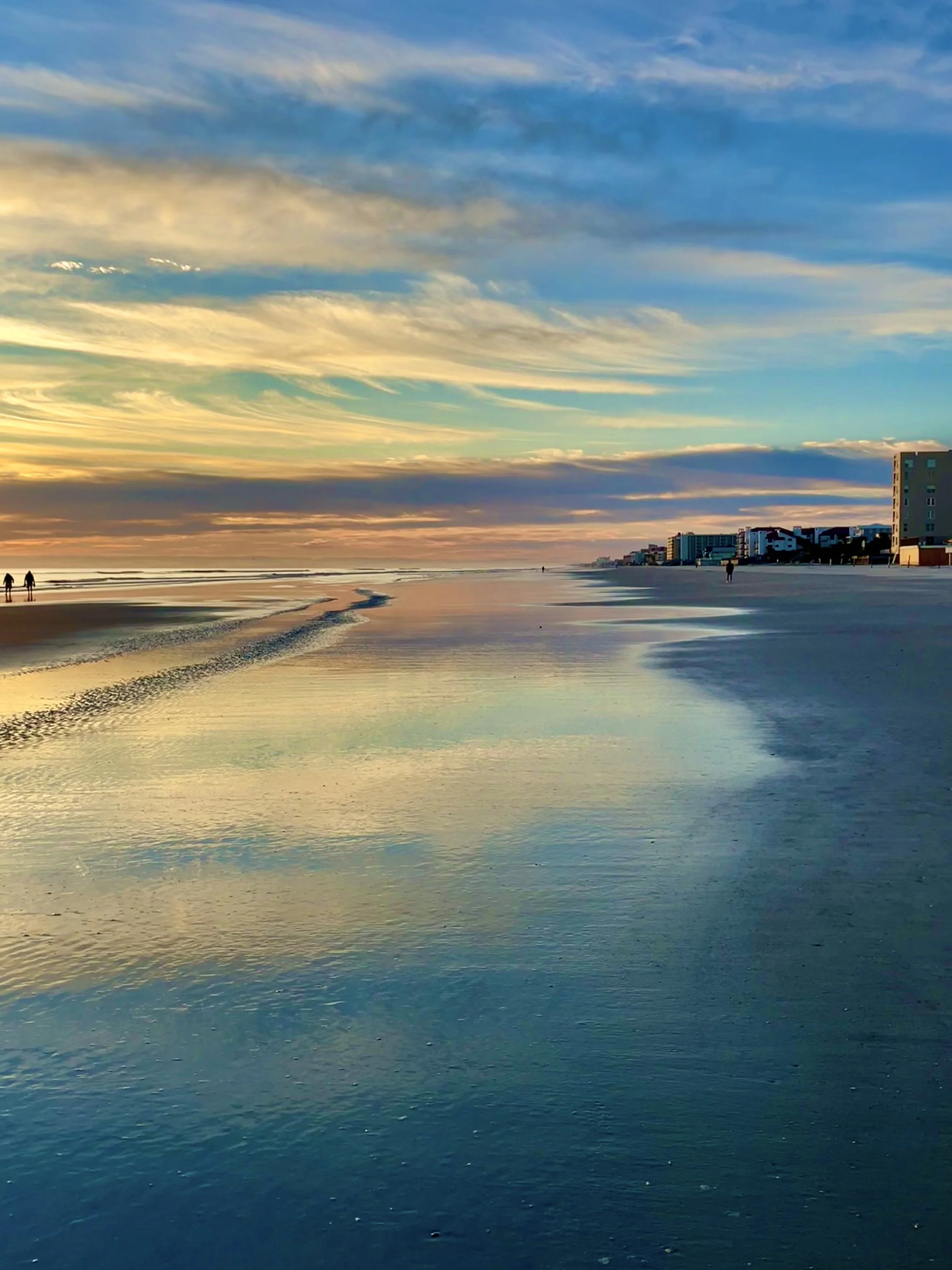 Sunrise over the ocean with a colorful sky and gentle waves up close.