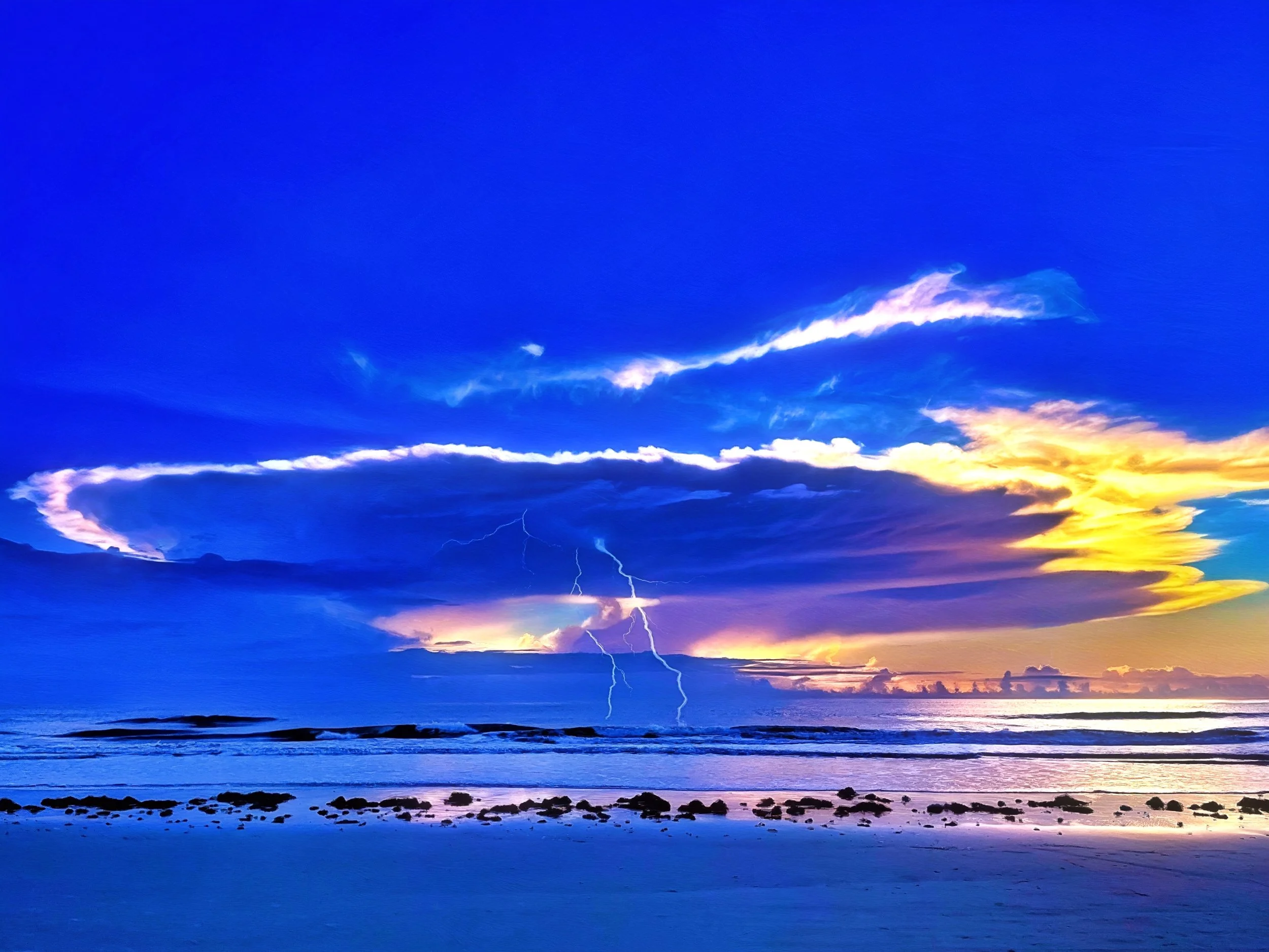 Sunrise over the ocean with a colorful sky and gentle waves up close.